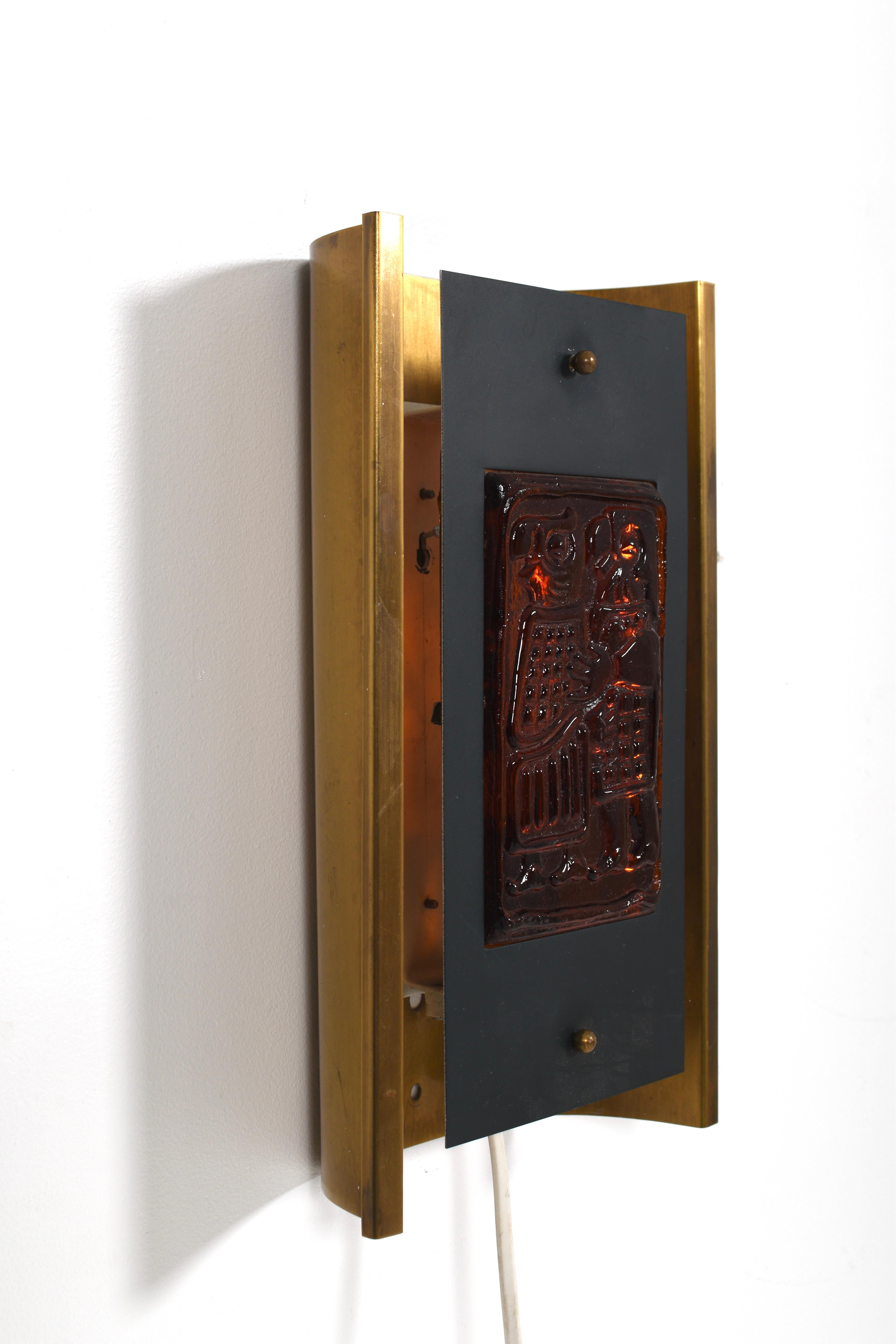 Aplique moderno de mediados de siglo diseñado por el aclamado artista sueco Erik Höglund para Boda Smide en la década de 1960. Este candelabro escultural presenta una atrevida combinación de materiales: un marco curvado de latón, una placa de metal