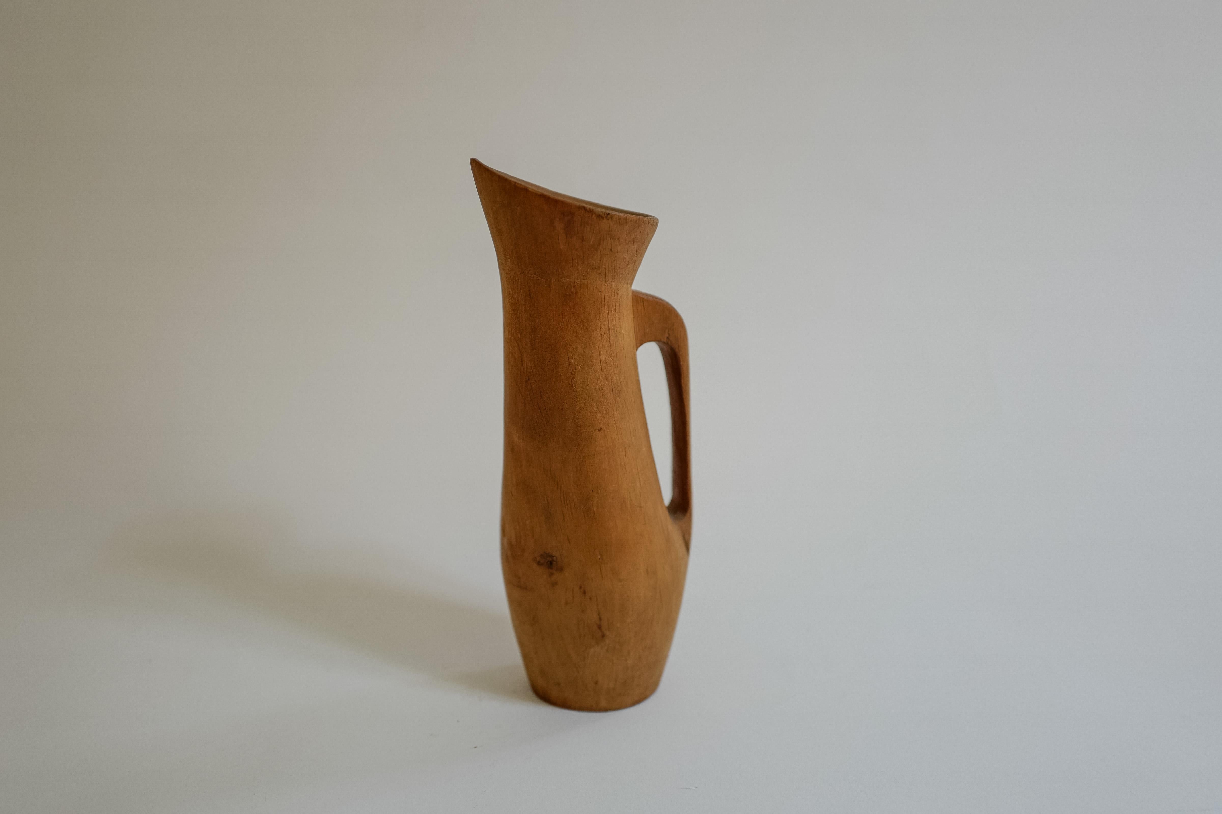 Esta jarra de madera sueca de mediados de siglo tallada a mano es un objeto decorativo bellamente elaborado que aporta elegancia natural a cualquier espacio. Con sus líneas elegantes y sus cálidos tonos de madera, esta jarra encarna el diseño