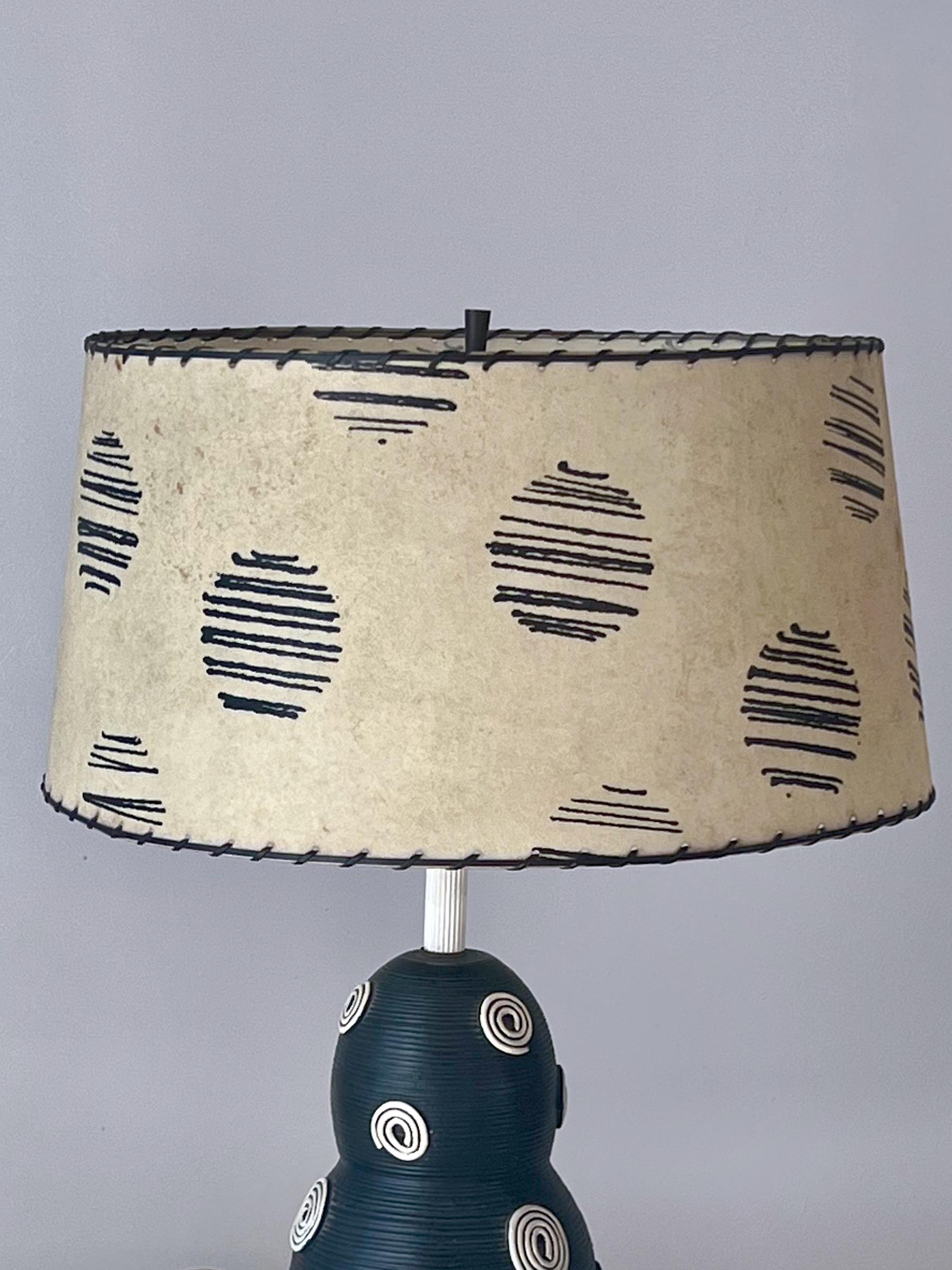 Utterly unique table lamp with custom lampshade. Protruding swirl pattern throughout, along with ridges to the ceramic. Tripod metal base supporting what is a very heavy piece. 