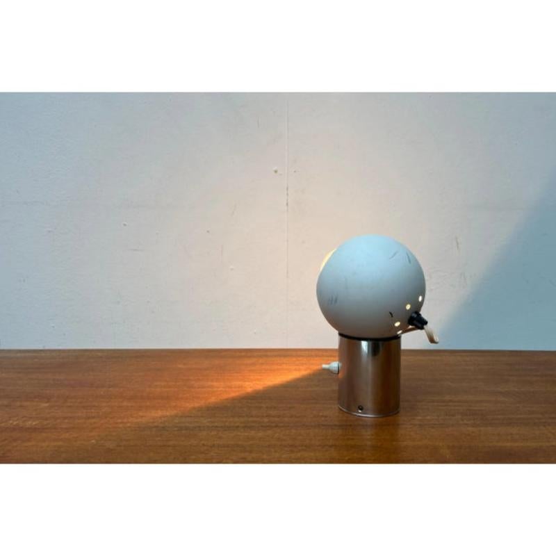Lampe de table ou applique suisse de l'ère spatiale avec réflecteur sphérique sur support magnétique.

Un détail frappant de cette lampe est sa tête sphérique. Celui-ci est maintenu par un aimant et peut donc être aligné de manière flexible. La