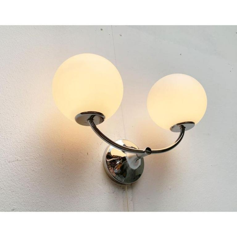 Eleganti lampade da parete di Temde per un progetto di E.R. Nele. Spesso attribuito erroneamente a Max Bill.

Classico e moderno senza tempo, soprattutto nella rara versione cromata. Due diffusori in vetro opalino si trovano all'estremità di un