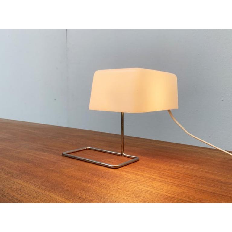 Very rare table lamp from temde in new condition.

A minimalist design. The simple translucent plastic shade is flexibly connected to the filigree base via a screwable clamp. This allows the shade to tilt and rotate. The base is made of a metal rod,
