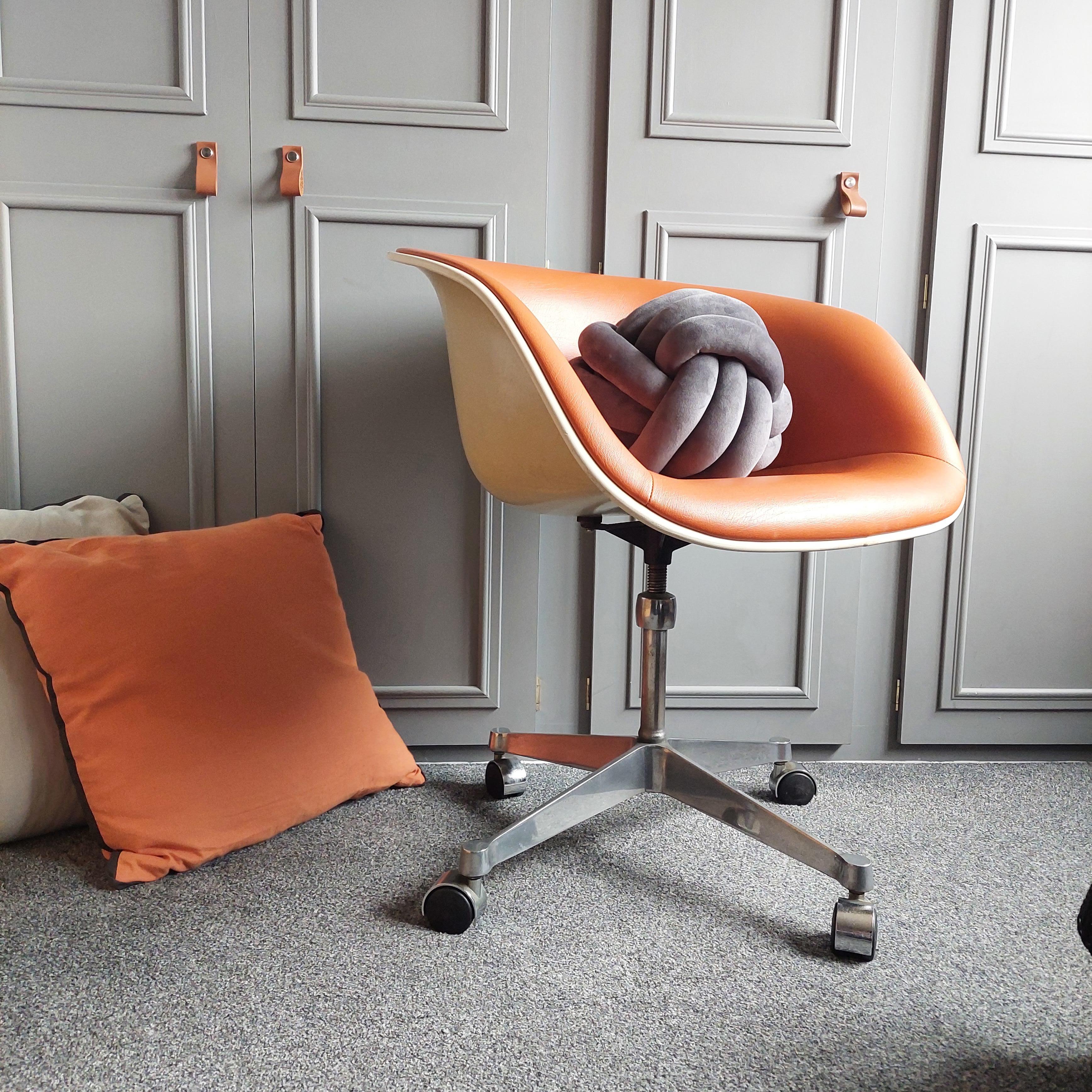 La Fonda chair by Charles and Ray Eames, designed in 1961.
Fabulous original orange leatherette atacched to the fiberglass body.
Swivel cast iron base with 4 star feet on wheels.
Adjustable seat height.

This armchair, American design icon of