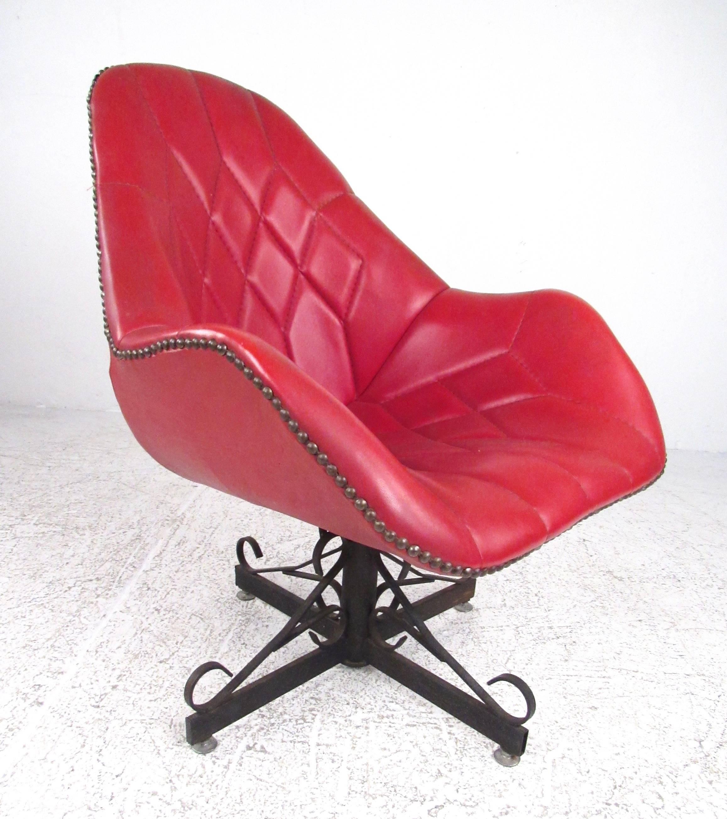 This unique vintage modern swivel chair features stitched red vinyl with brass upholstery buttons around the trim. Substantial cast iron swivel base adds gothic appeal to this midcentury side chair. A striking and unusual addition to home living