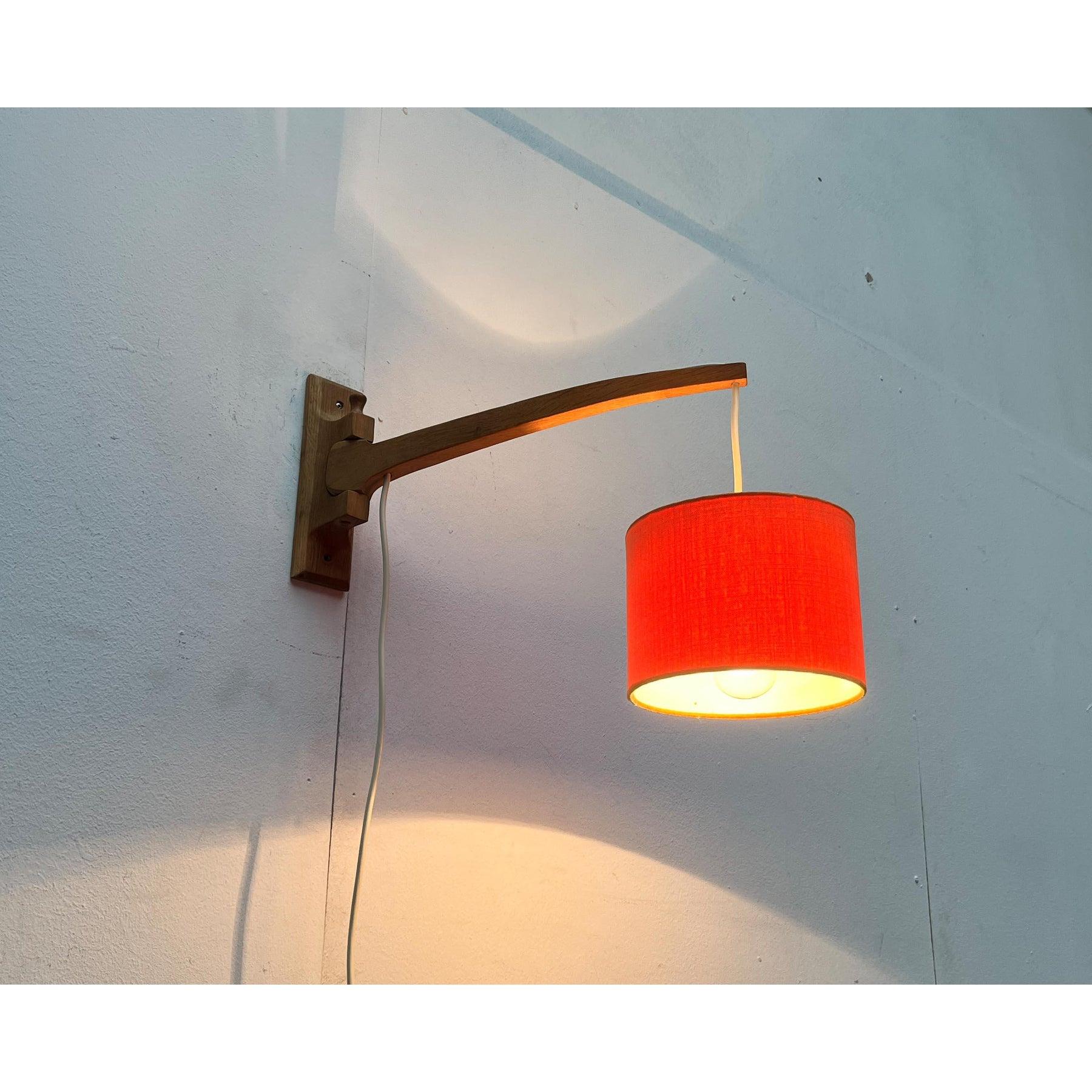 Mid Century wall lamp with swiveling arm.

The cantilevered arm is made of wood and is pivotably mounted in the wall base. The cable is routed in a groove on the top. The cable runs down through a hole at both ends of the arm. On one side to the