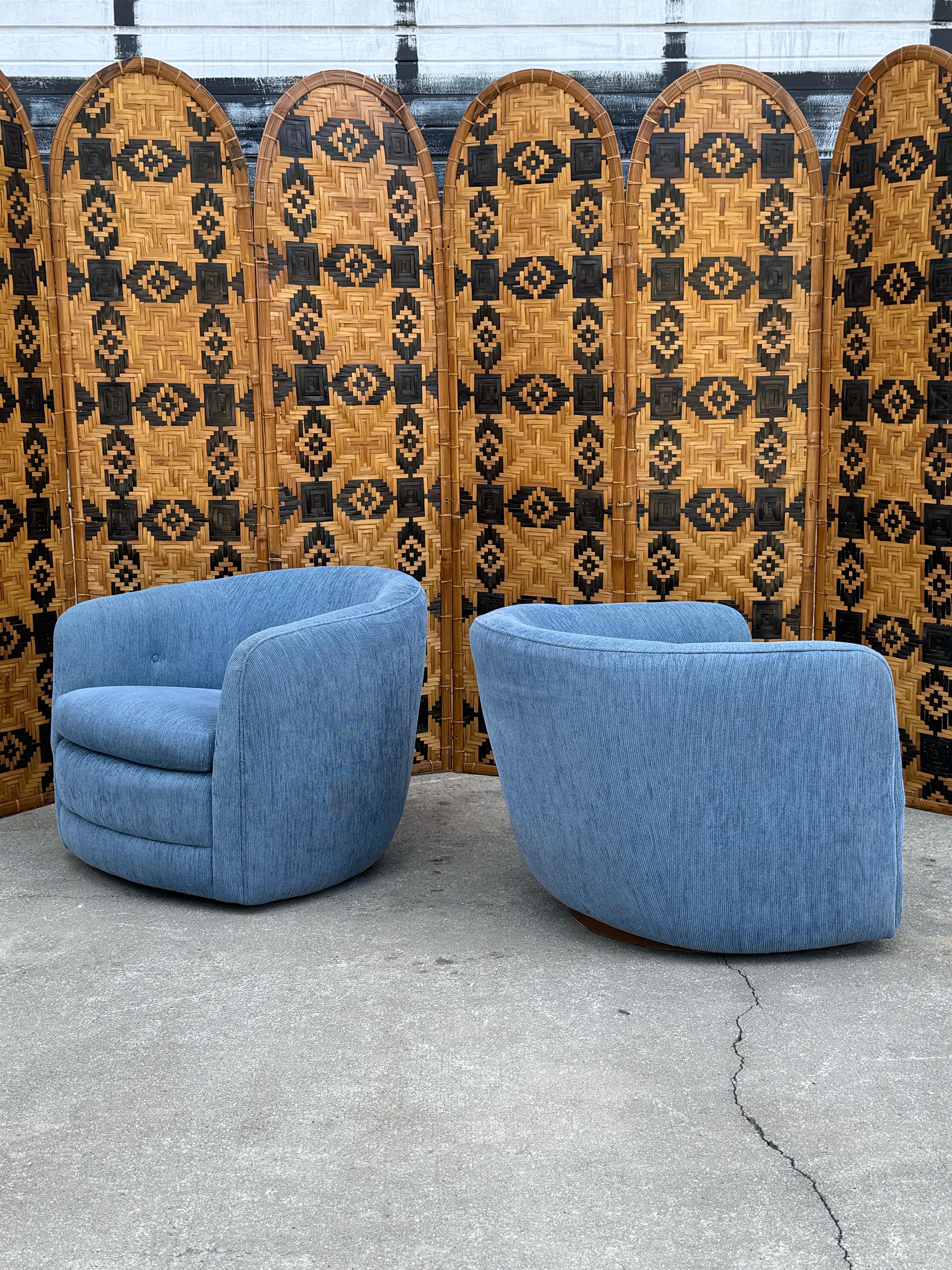 A pair of mid-century swivel AND rocking chairs designed by Milo Baughman for Thayer Coggin. This pair features a round back and profile that allows for maximum comfort. Enjoy the ability to swivel and rock. Sitting atop rounded sleek plinth bases.
