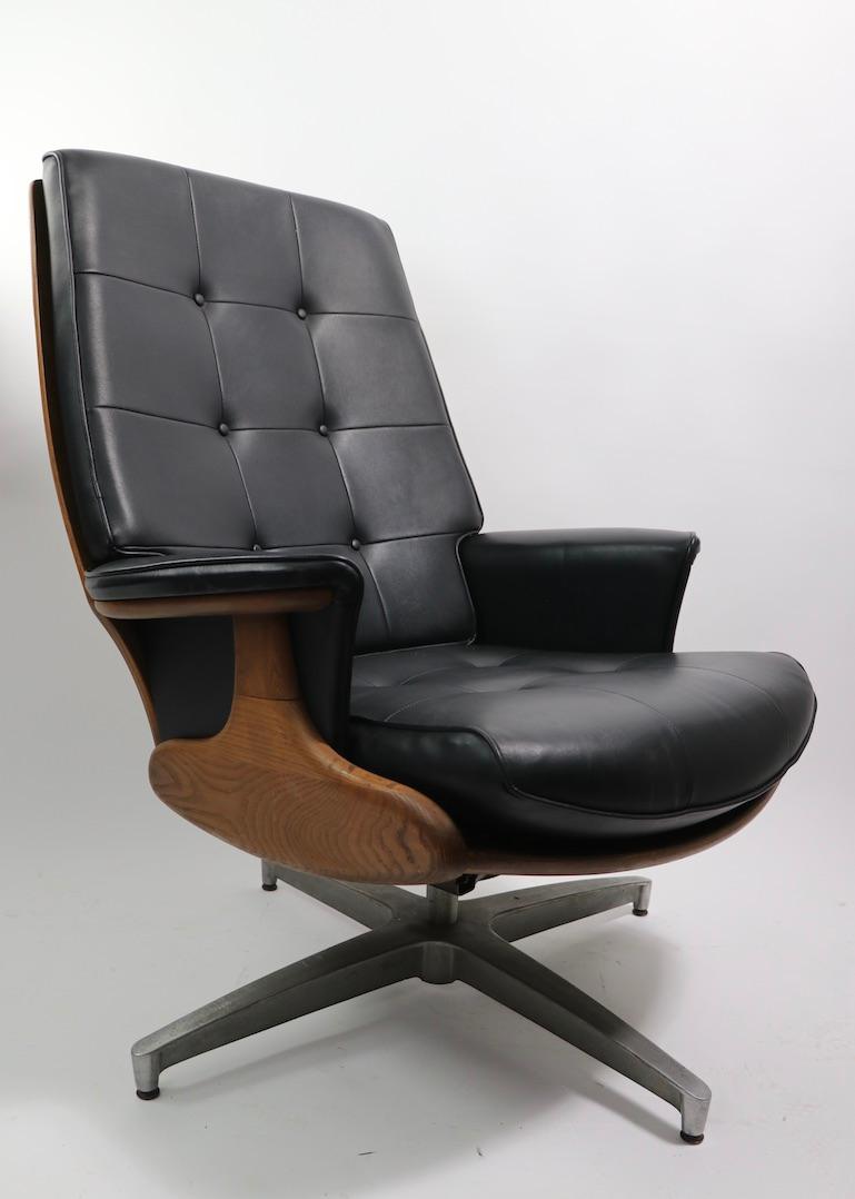 Classic Mid-Century Modern swivel, tilt lounge chair by Heywood Wakefield, after Eames. The chair is constructed of solid wood (oak and walnut) with vinyl seat and backrest cushions, on cast metal star base. This example is in very good, original