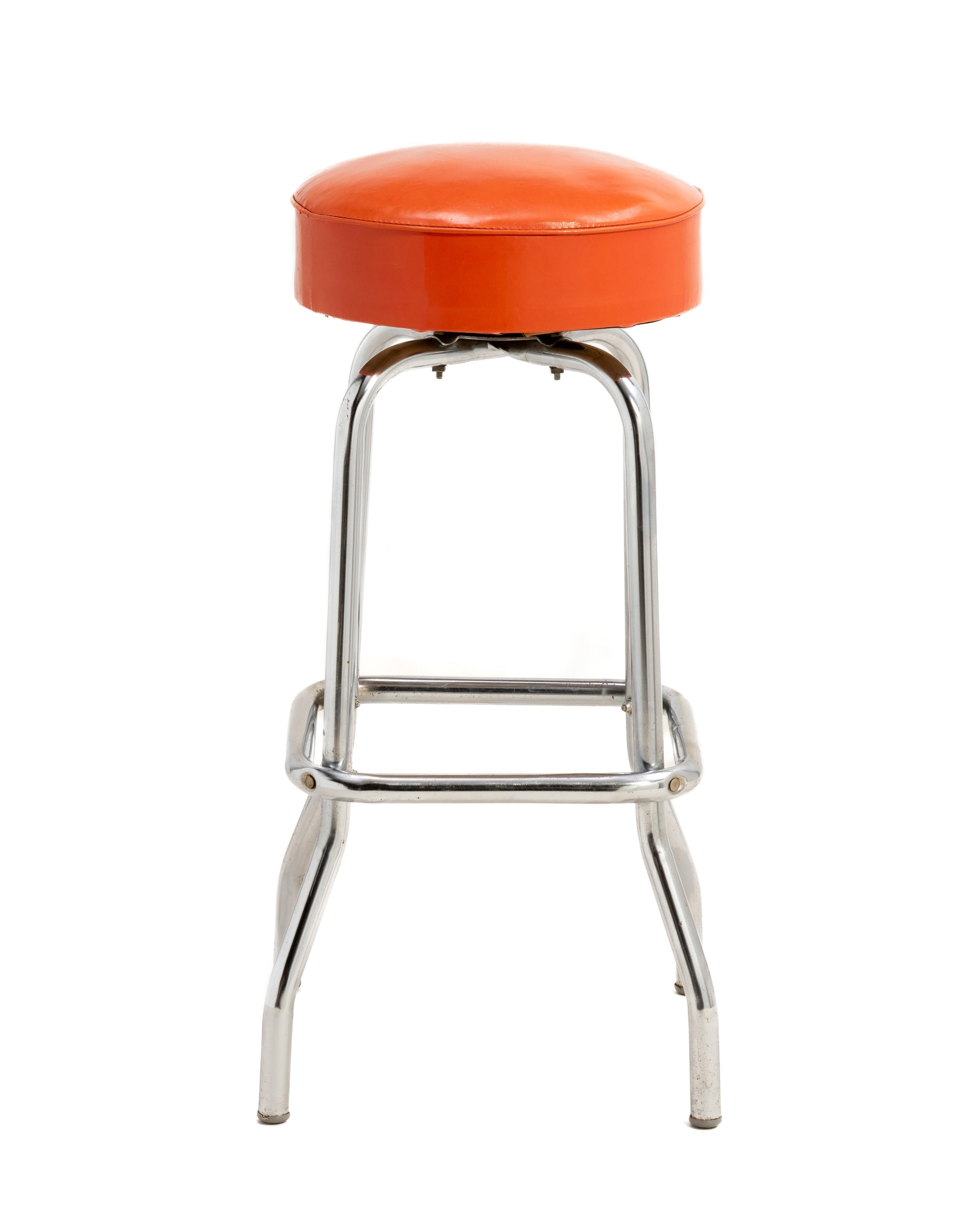 A set of four Mid Century barstools with chrome legs and the original orange vinyl seats. These iconic barstools are in remarkable, original condition.