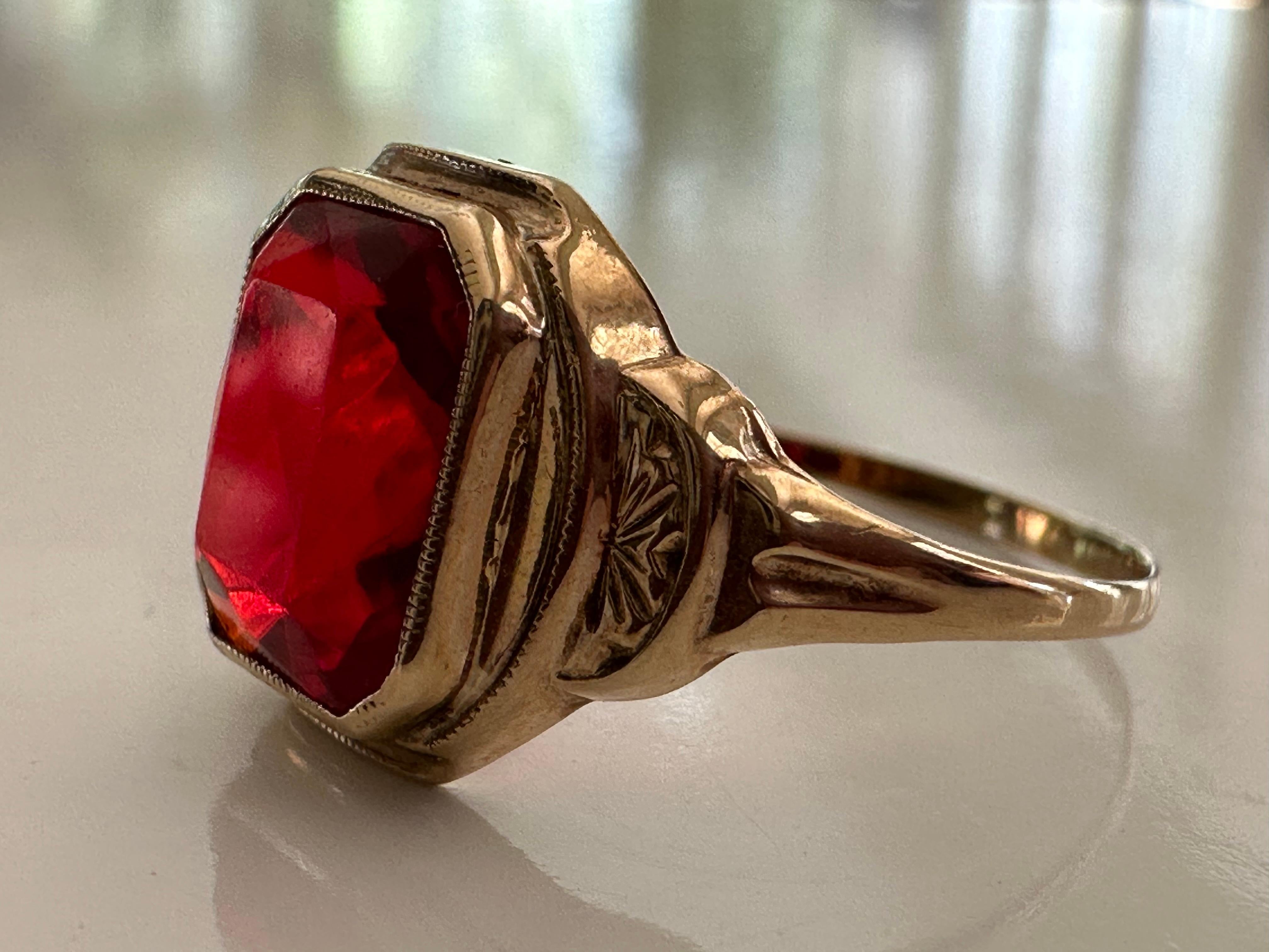 Crafted in 1950, this mid-century gem from American jewelry manufacturers Budlong Docherty & Armstrong, Inc features an emerald-cut synthetic ruby measuring approximately 2.00 carats set in a 10kt yellow gold band with delicate piercing. Marked