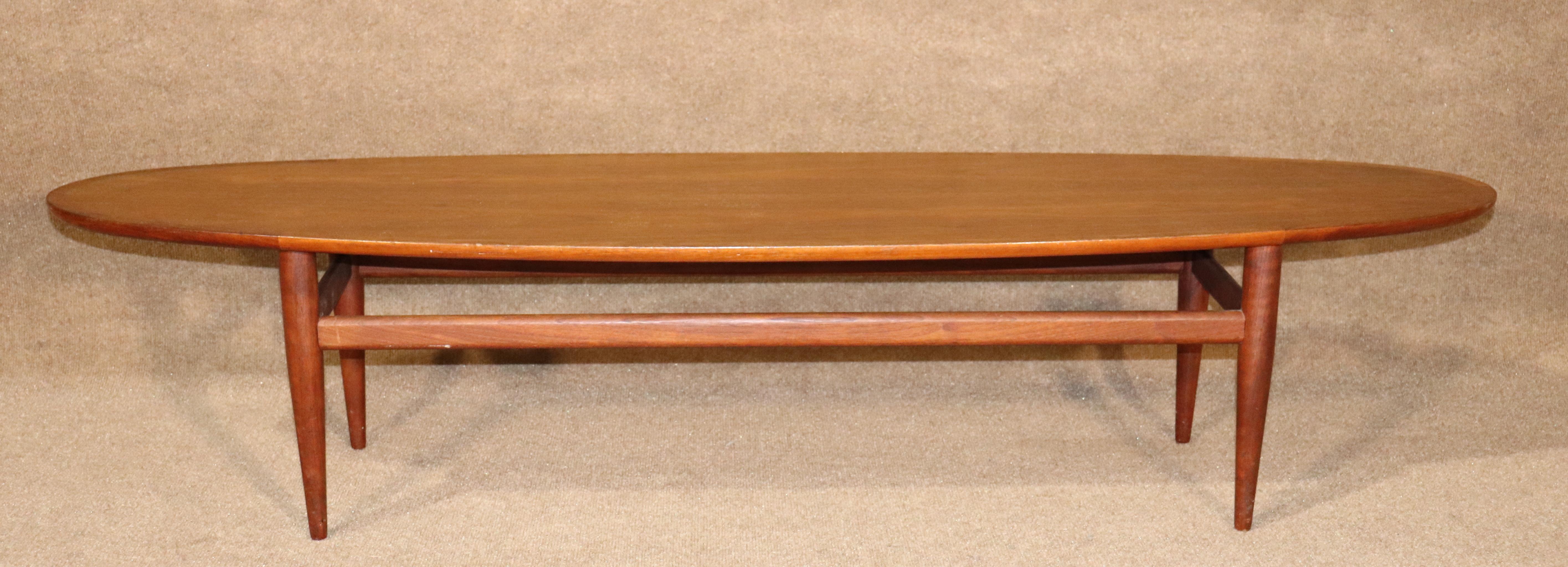 Oval surfboard coffee table by Henredon with added walnut trim and tapered legs.
Please confirm location.