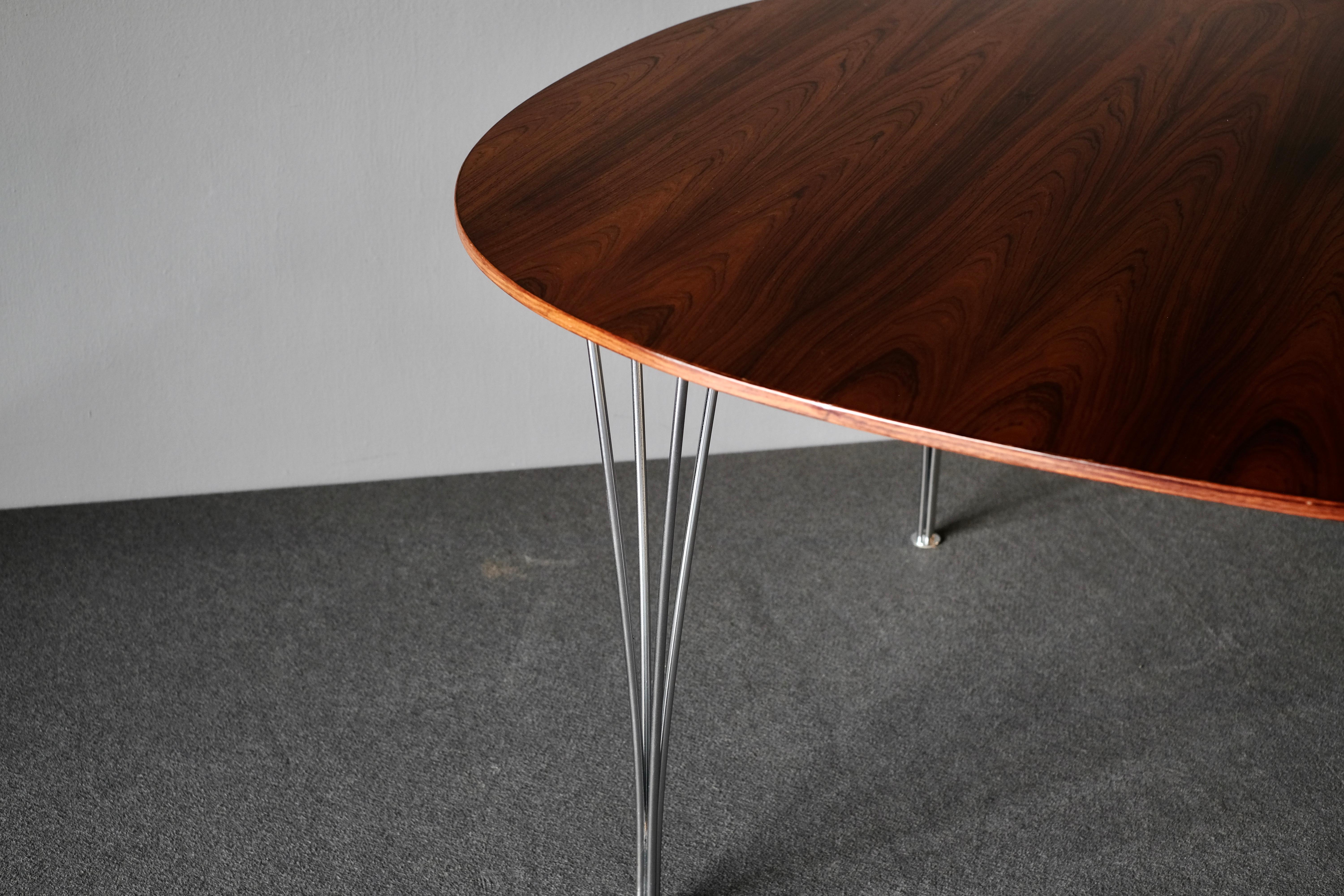 Dining table by designed by Piet Hein and Bruno Mathsson and manufactured by Fritz Hansen. It is in wonderfully patinated Brazilian rosewood and has chromed steel legs. The maker’s mark is stamped on the base.