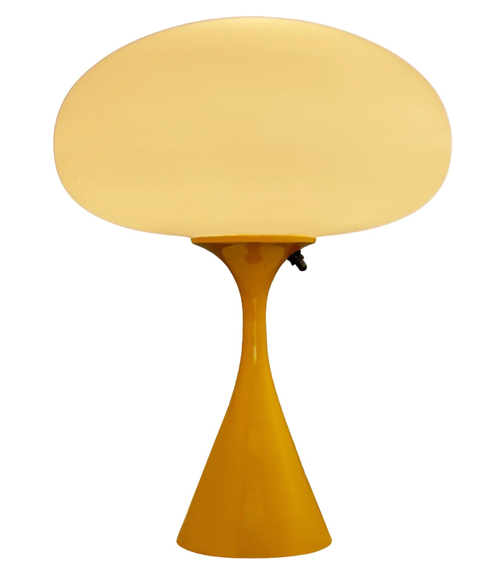 THIS ITEM IS ELIGIBLE FOR FREE SHIPPING!

A sleek stemlite table lamp made by Design Line. It features a cast aluminum main base in a conical form. The lamp base is finished in a retro mustard yellow color. The frosted glass lamp shade is hand blown