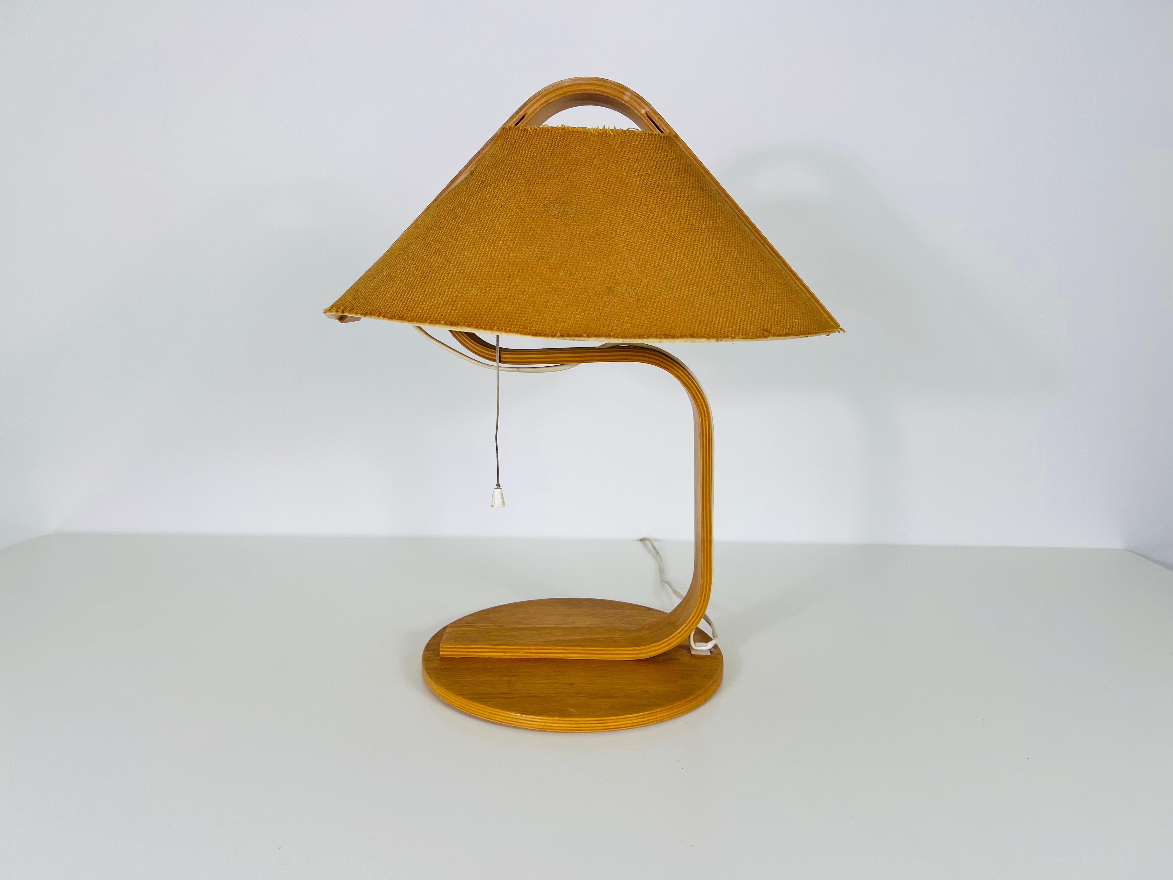 La lámpara de sobremesa Domus, de los años 60, es una impresionante pieza de madera fina y curvada, que encarna los principios de diseño elegante y funcional del movimiento Bauhaus. Aunque tiene algunos daños en la pantalla interior, estas