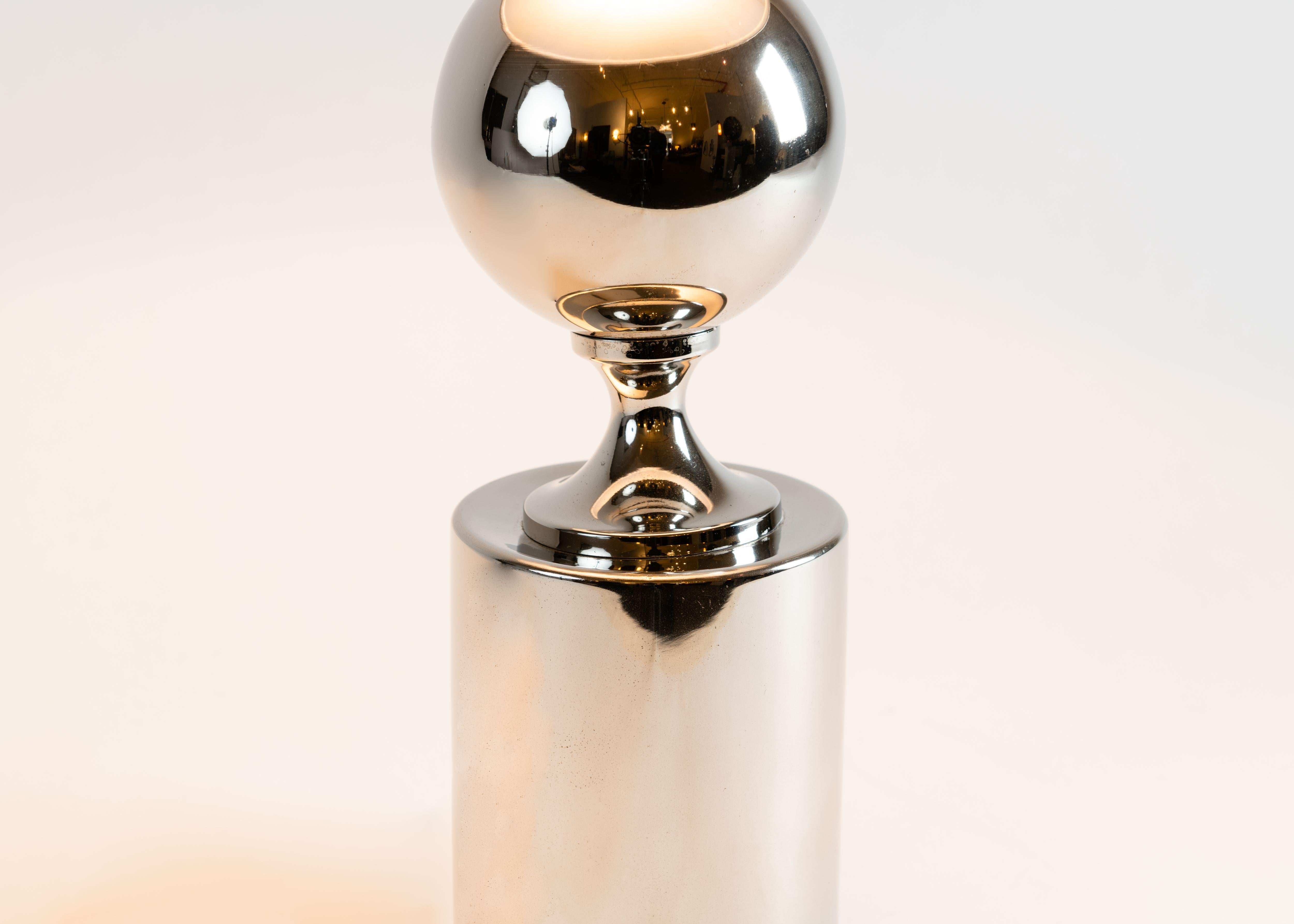 This elegant Philippe Barbier table lamp is composed of two mirror-polished orbs on a cylindrical base. Versions of this lamp have been included in the set design of a number of films including Gregory Peck and Laurence Olivier's The Boys from