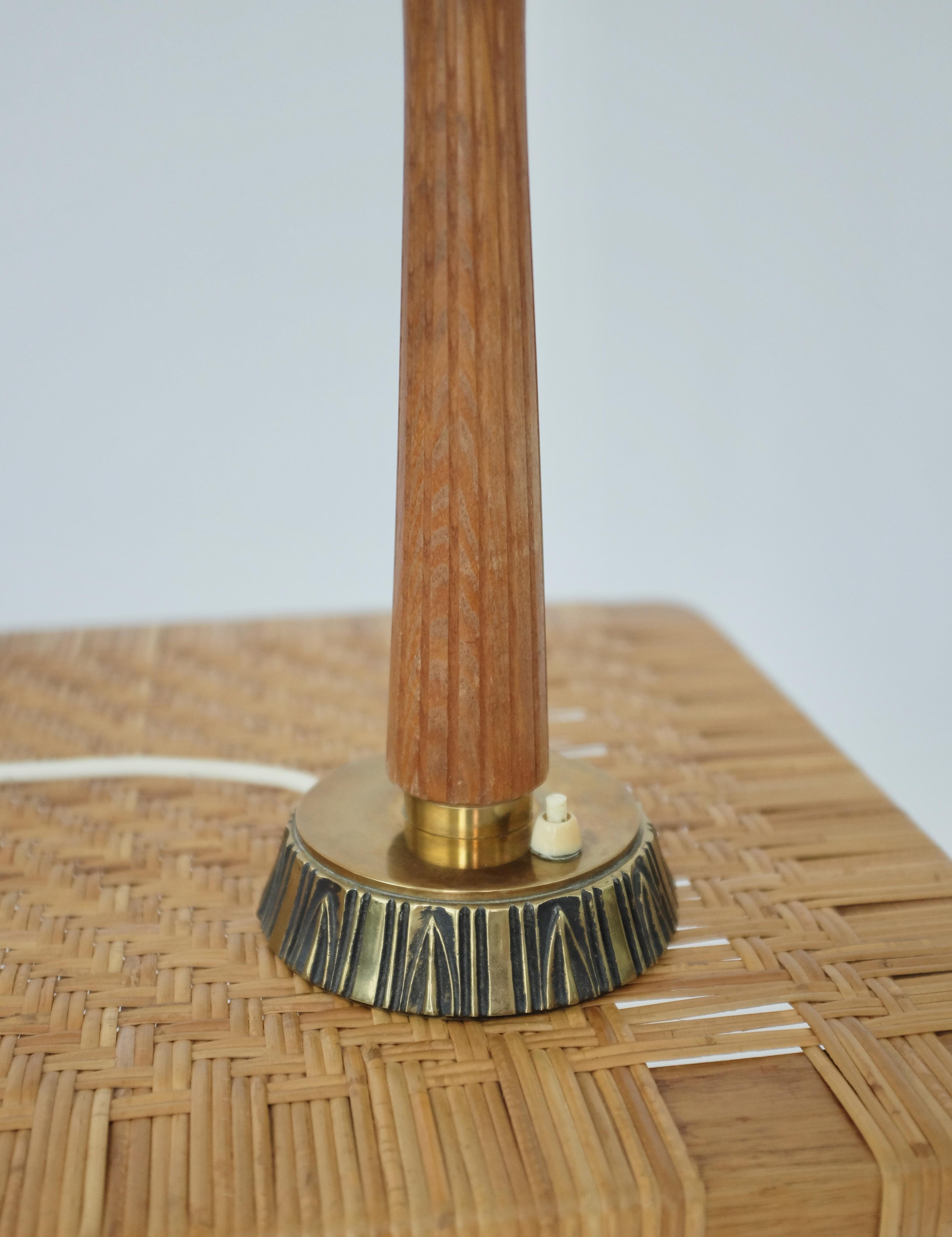 Beautiful 1950's Teak and Brass table lamp by Sonja Katzin for ASEA. Teak handle and brass foot with carved stripes pattern. Label with ASEA model 1141. In a very good condition with a nice shine to the brass and a new lamp shade. Sonja Katzin was a