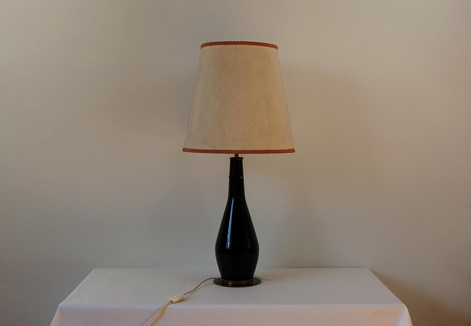 Lampe de table midcentury avec structure en verre noir et laiton et abat-jour en tissu. Produit par la société italienne Stilnovo dans les années 1950.

Le logo du fabricant est apposé sur l'interrupteur.

Cette lampe peut être équipée d'une
