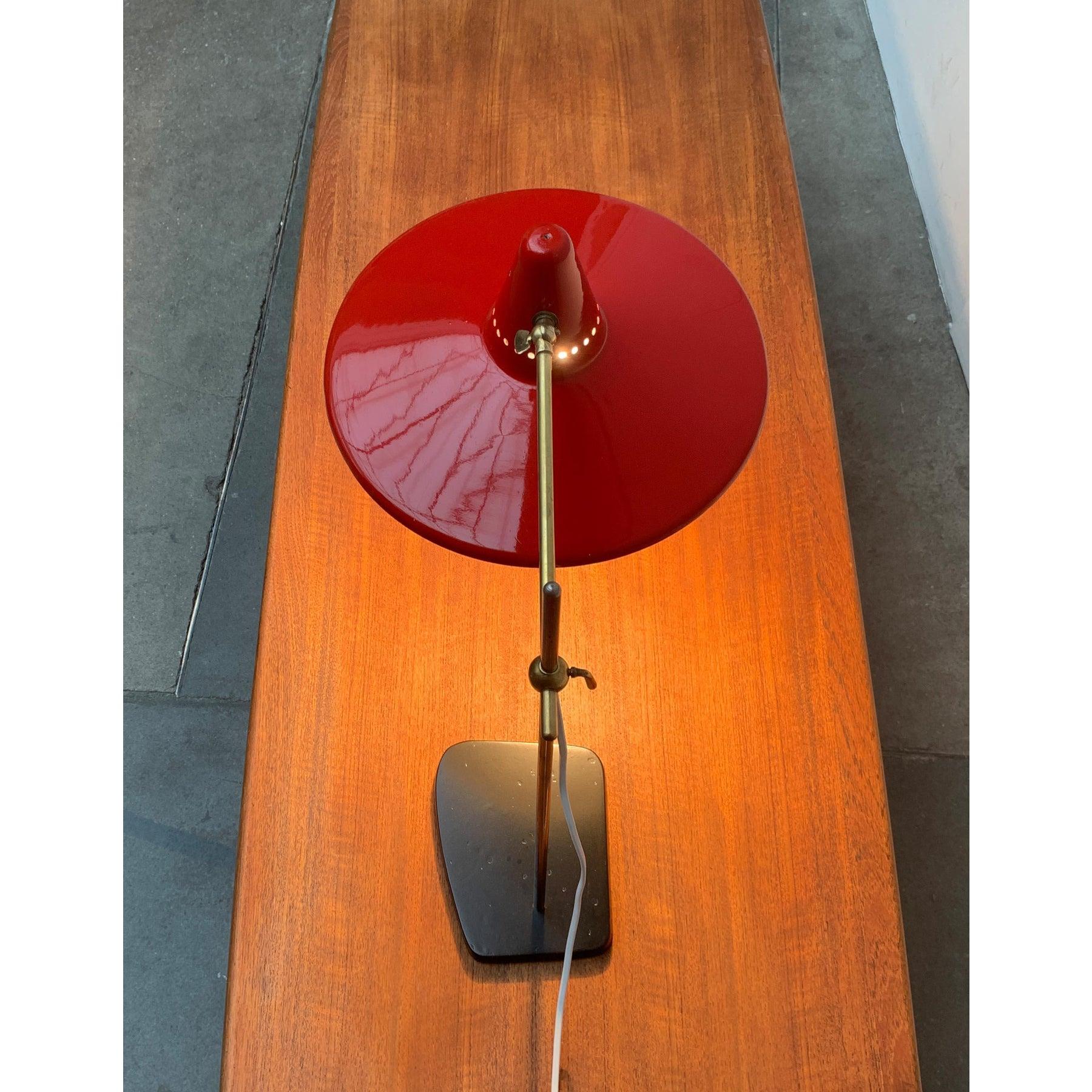Lampe de table du milieu du siècle avec grand écran.

Ce qui frappe, c'est le grand écran rouge dans un design particulièrement plat. Il est assis sur un bras en laiton, qui peut être enfilé et glisser sur un arbre en métal. Un support sert à la