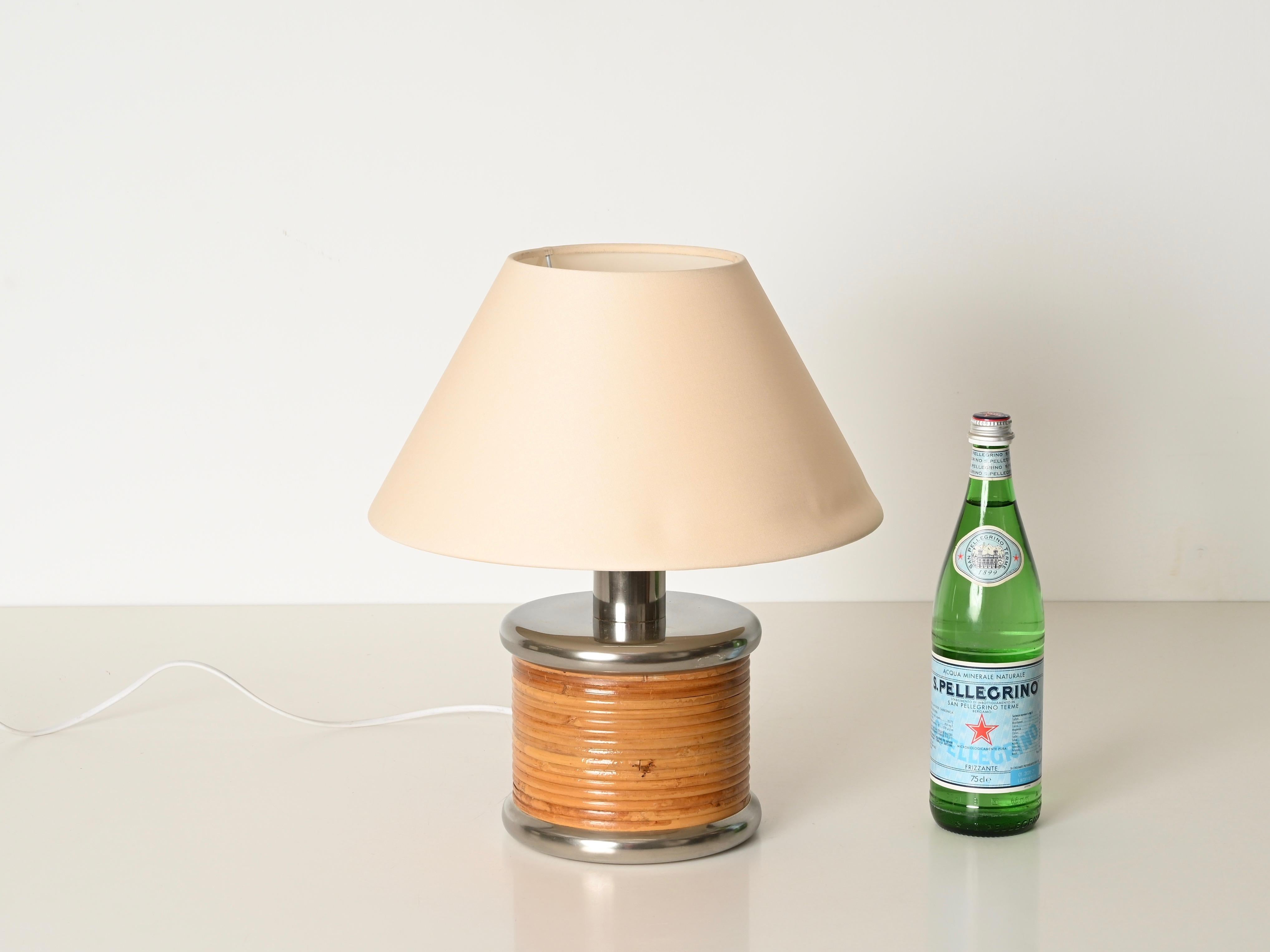 Preciosa lámpara de sobremesa de mediados de siglo totalmente fabricada en ratán curvado y metal cromado, completada con una pantalla de algodón. Esta encantadora y singular lámpara orgánica fue diseñada por Vivai del Sud y producida en Italia