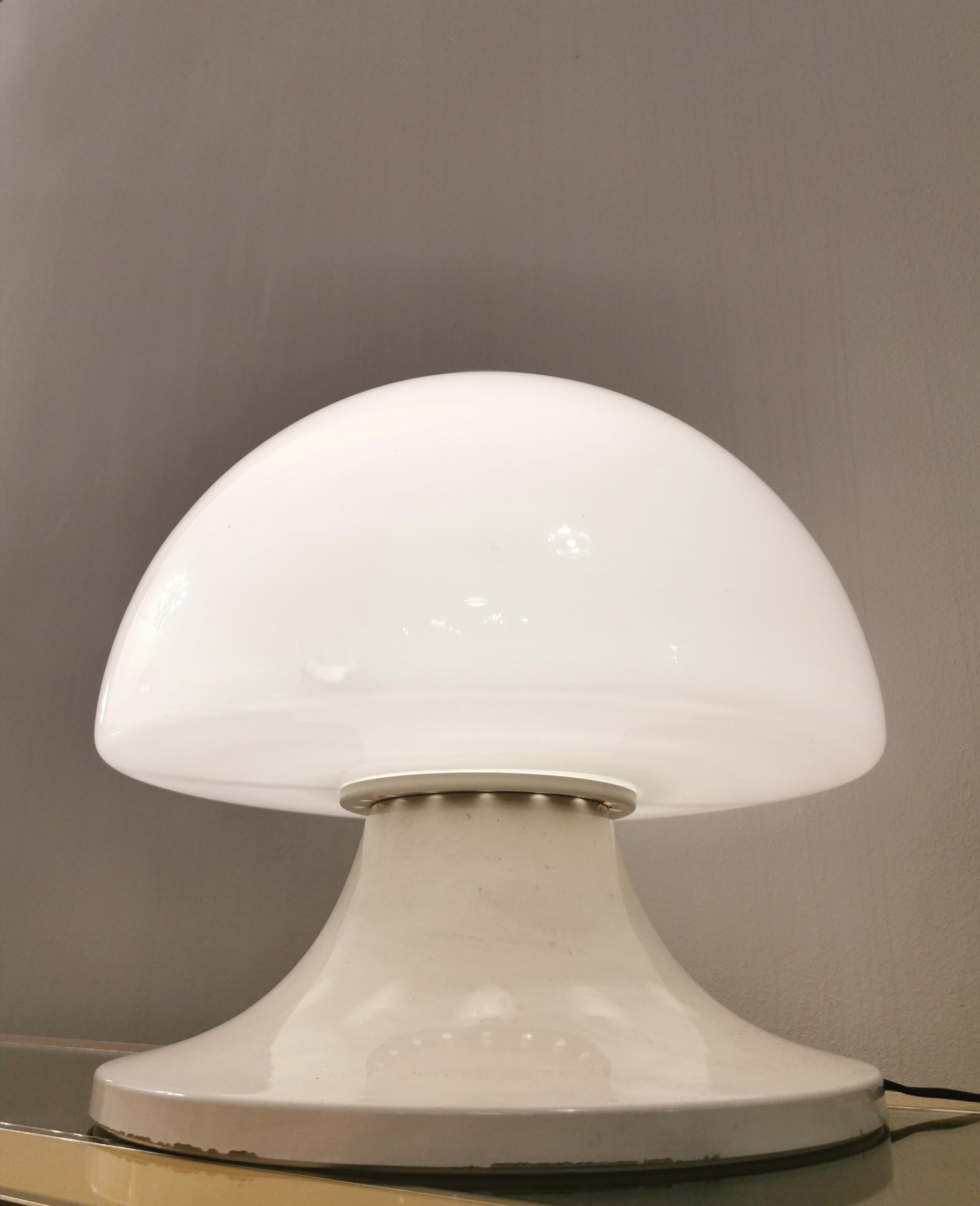 Particular table lamp with 1 light E27 in enamelled aluminum that supports a half-sphere diffuser in milky glass. A satin aluminum accessory is screwed above the diffuser. Made in Italy in the 1960s.

 