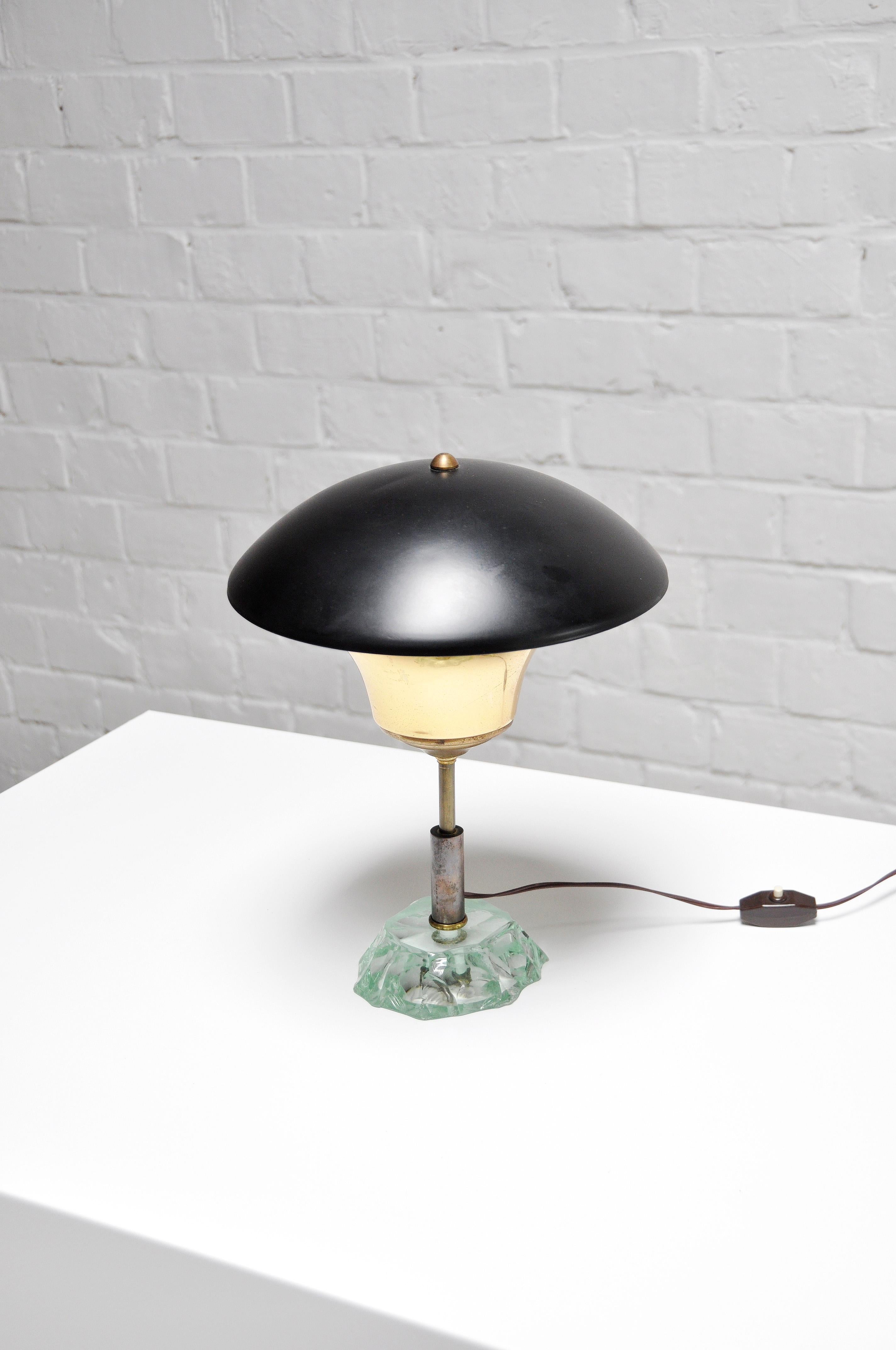 Mid-century Italian table lamp out of the 1950’s. The lamp features an adjustable swiveling mushroom shade with its original black lacquered paint. It has a beautiful thick crystal glass base. The swiveling and rotatable dome shaped lamp shade can