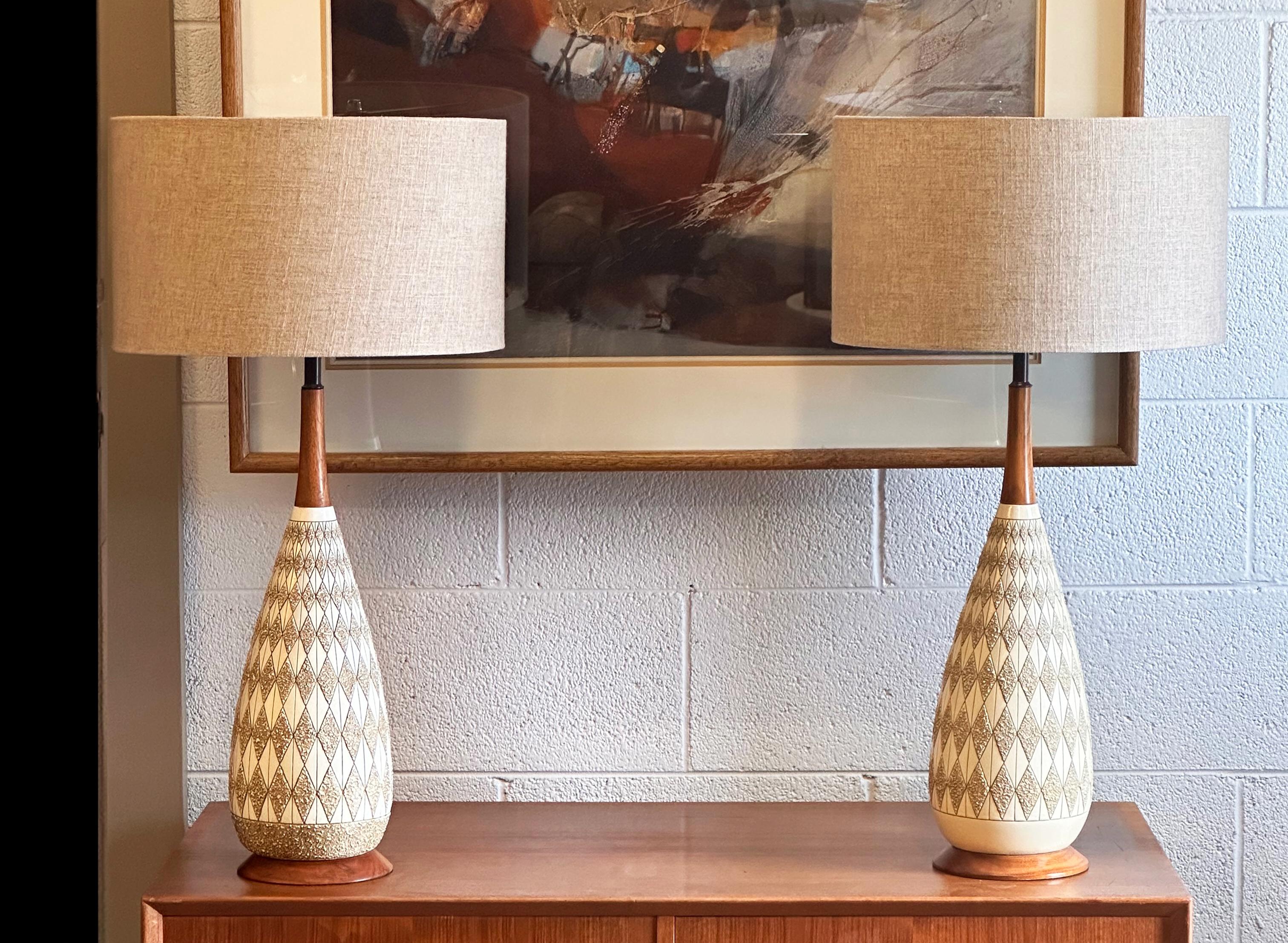 Una coppia di lampade da tavolo con corpo in ceramica a texture lavica a motivi arlecchino e steli e basi in teak. Quartite Creative Corp., USA, anni '60.

Nuove tonalità.

Dimensioni della lampada: 20,5