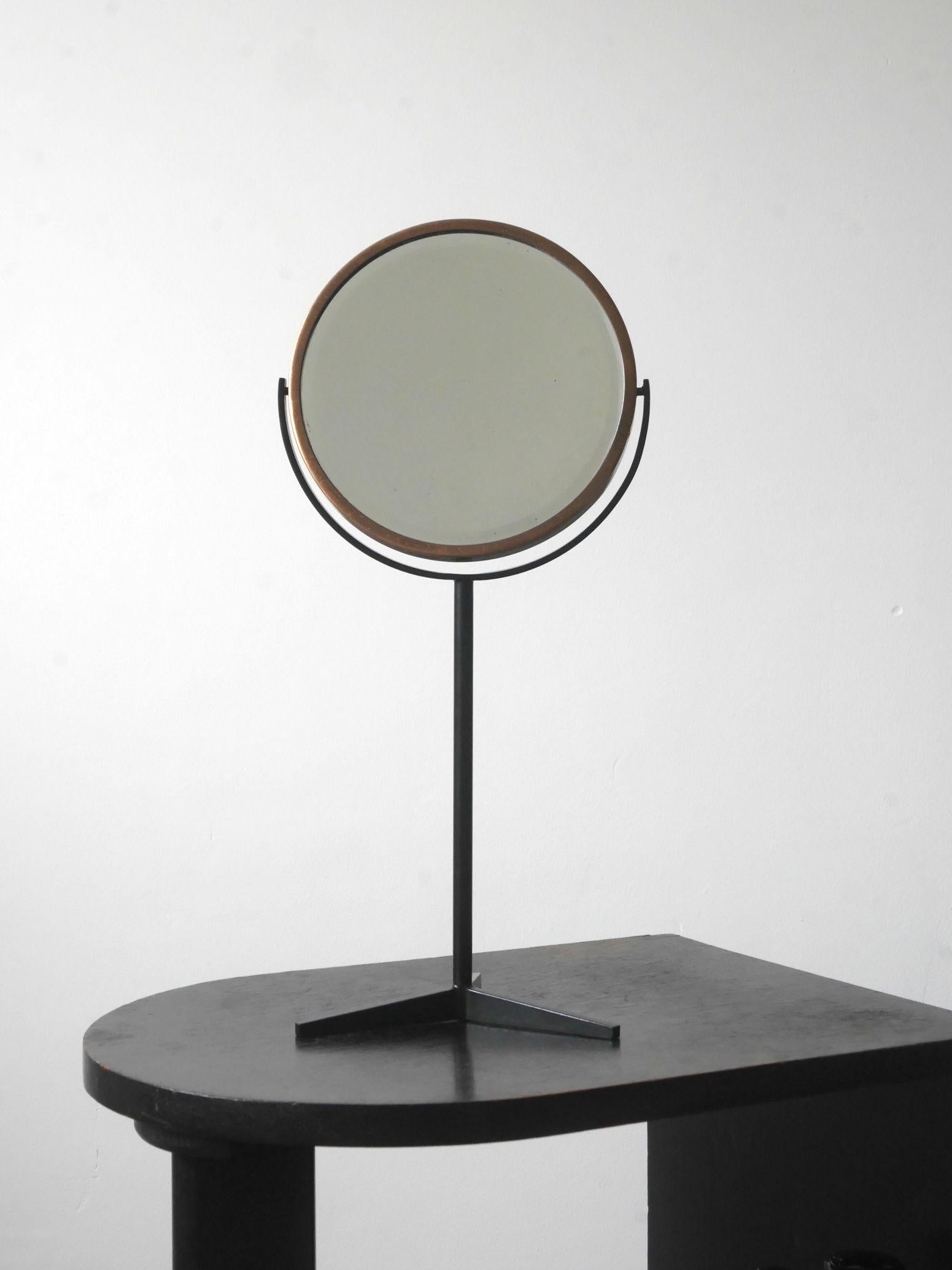 Model PC180 table mirror designed in 1961 by Colin Beales and made by Peter Cuddon, England. 

Made of black painted steel with a slender frame and tripod base. The bevelled mirror is set in a brass frame and swivels round fully. 

A beautiful