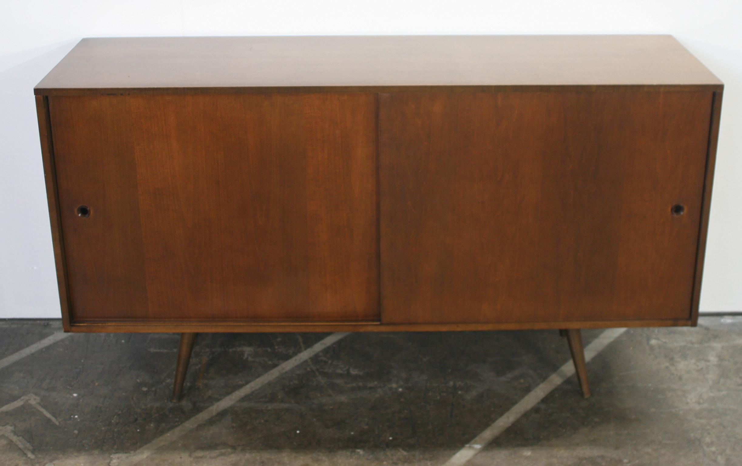 Beautiful midcentury tall credenza by Paul McCobb circa 1950 Planner Group #1514 has 1 adjustable shelves w/pins with 1 drawer on the left side and 3 drawers on the right side. Solid maple construction has a dark walnut finish. All original walnut