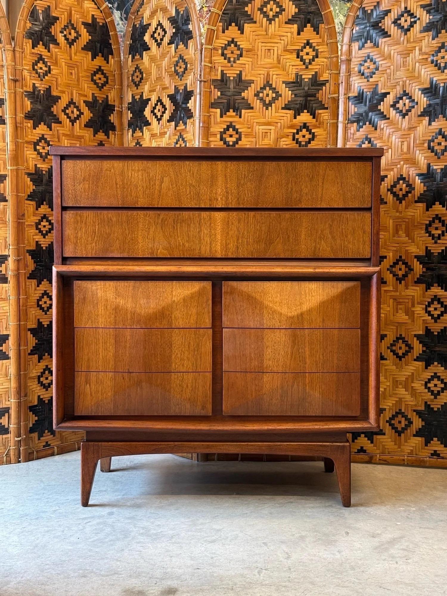 Comò alto di metà secolo prodotto da United Furniture. Questo pezzo fa parte della collezione Diamond Front. Il nome è giusto per i suoi cassetti anteriori intagliati in modo geometrico che creano un motivo a forma di diamante. Dispone di sei