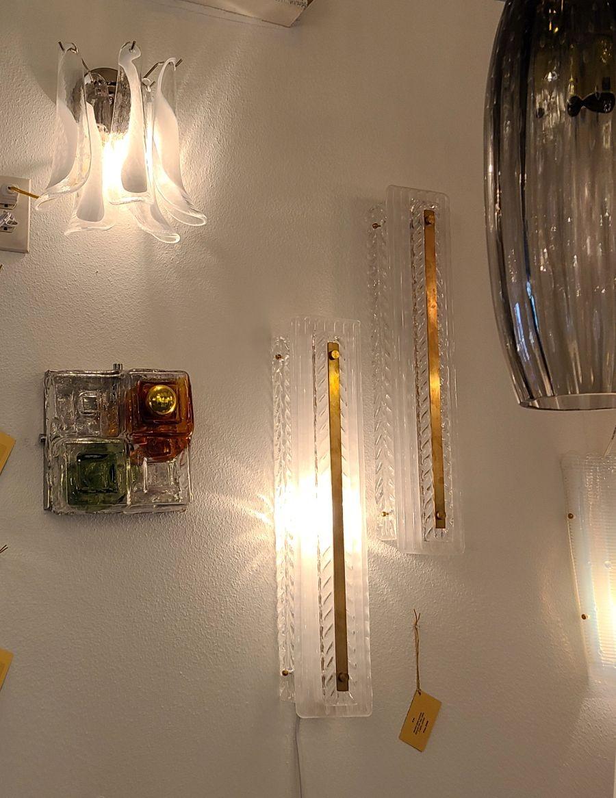 Ein Paar Murano-Glasleuchten im Stil der Jahrhundertmitte, Italien 1990er Jahre.
Das Paar ist aus klarem, durchscheinendem, handgefertigtem Murano-Glas mit Chevron-Muster und Messingbeschlägen gefertigt.
Die Wandleuchter haben jeweils 2 Lampen und