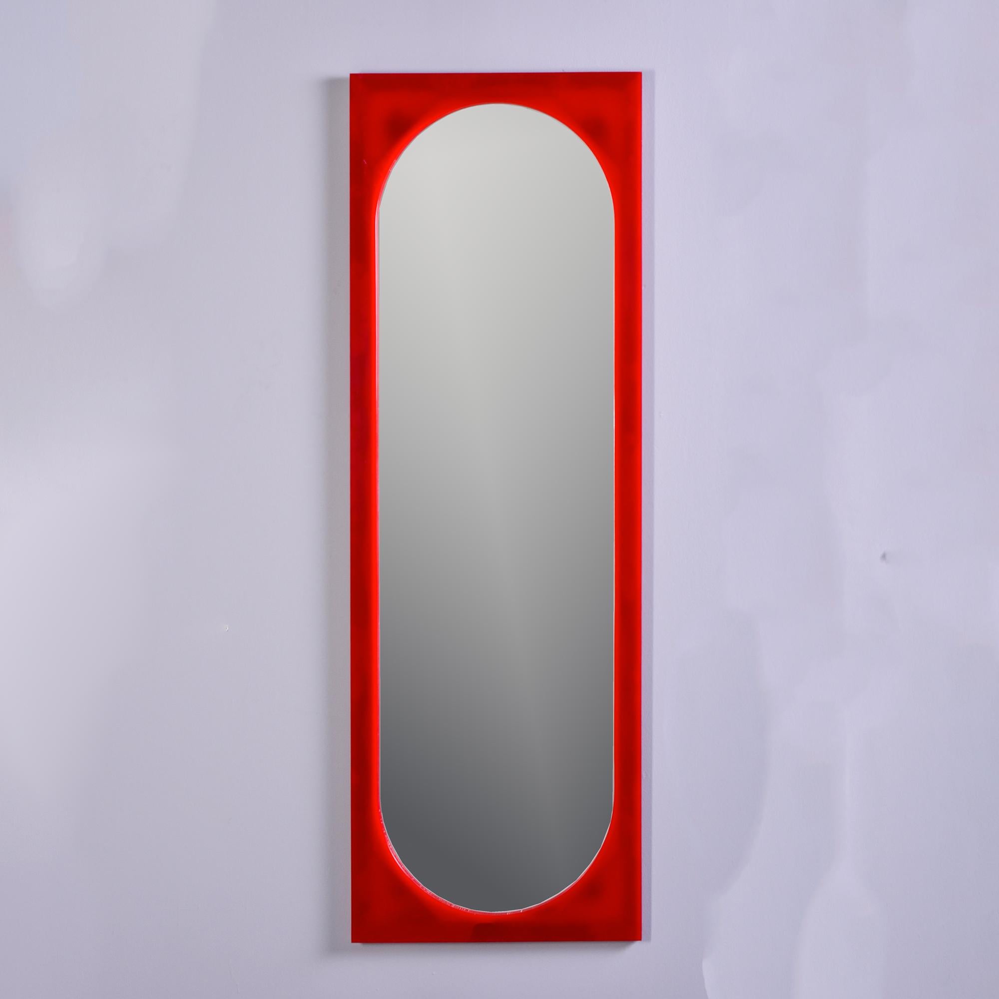 Found in Italy, this circa 1980s tall, slender rectangular mirror is attributed to designer Anna Castelli for Kartell and features a true red plastic frame with an oval cut out for the mirror. Very good vintage condition with only minor scattered