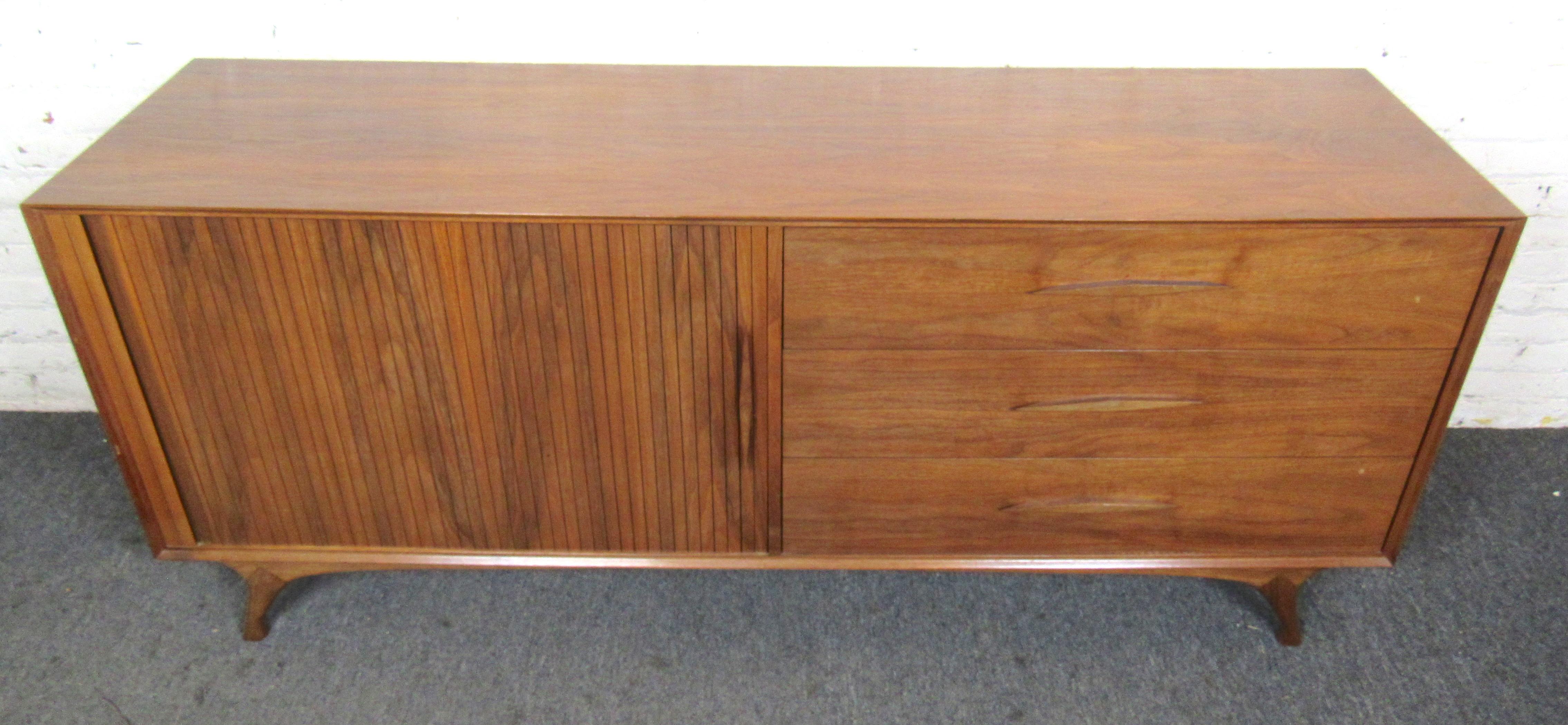Unique Mid-Century Modern cabinet with tambour door that reveals cabinet storage and three wide drawers. Complete with sculpted wood handles and legs.
(Please confirm location NY or NJ).