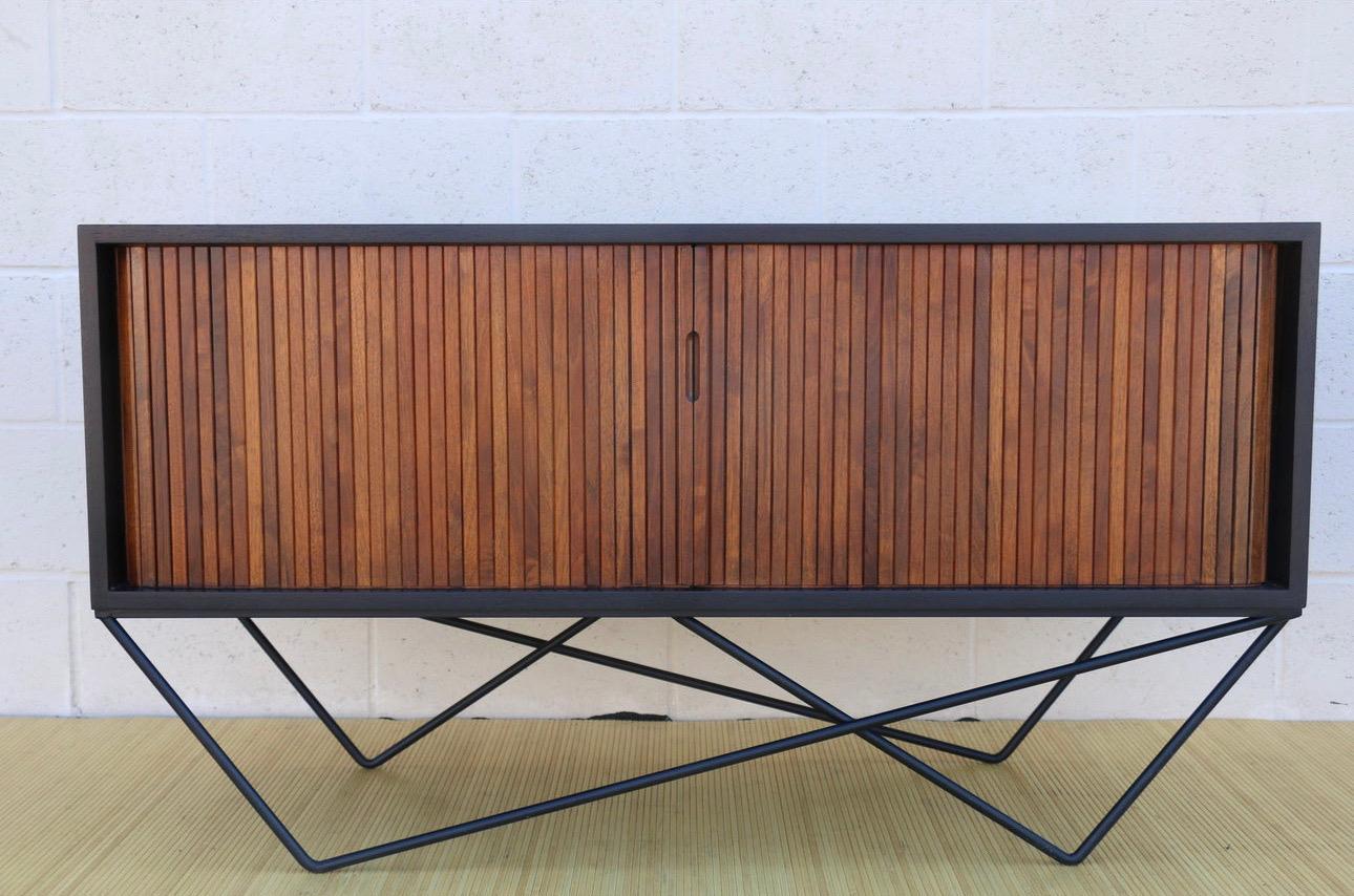 Wonderful Mid Century tambour-door low credenza made of walnut wood and custom made wrought iron base. Manufactured in the 1960’s. This credenza is in excellent condition. Its tambour doors open perfectly. It has been refinished and it is very well