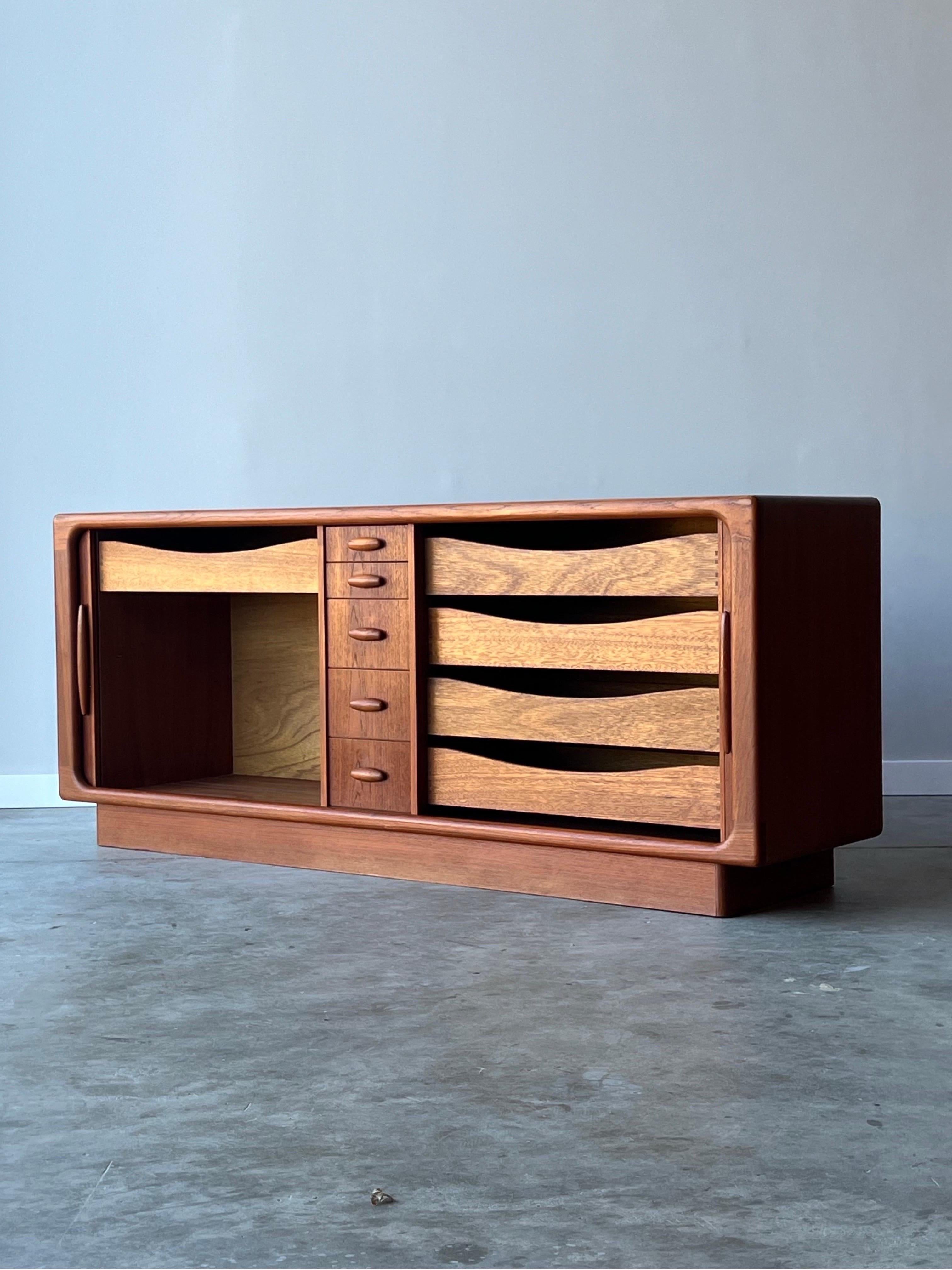 Elegant and stately case piece made by Dyrlund, Denmark. Made from Danish teak wood, circa 1970s. This piece could be used as a traditional dresser, sideboard, or living room credenza as it is both aesthetically and functionally versatile. Tambour