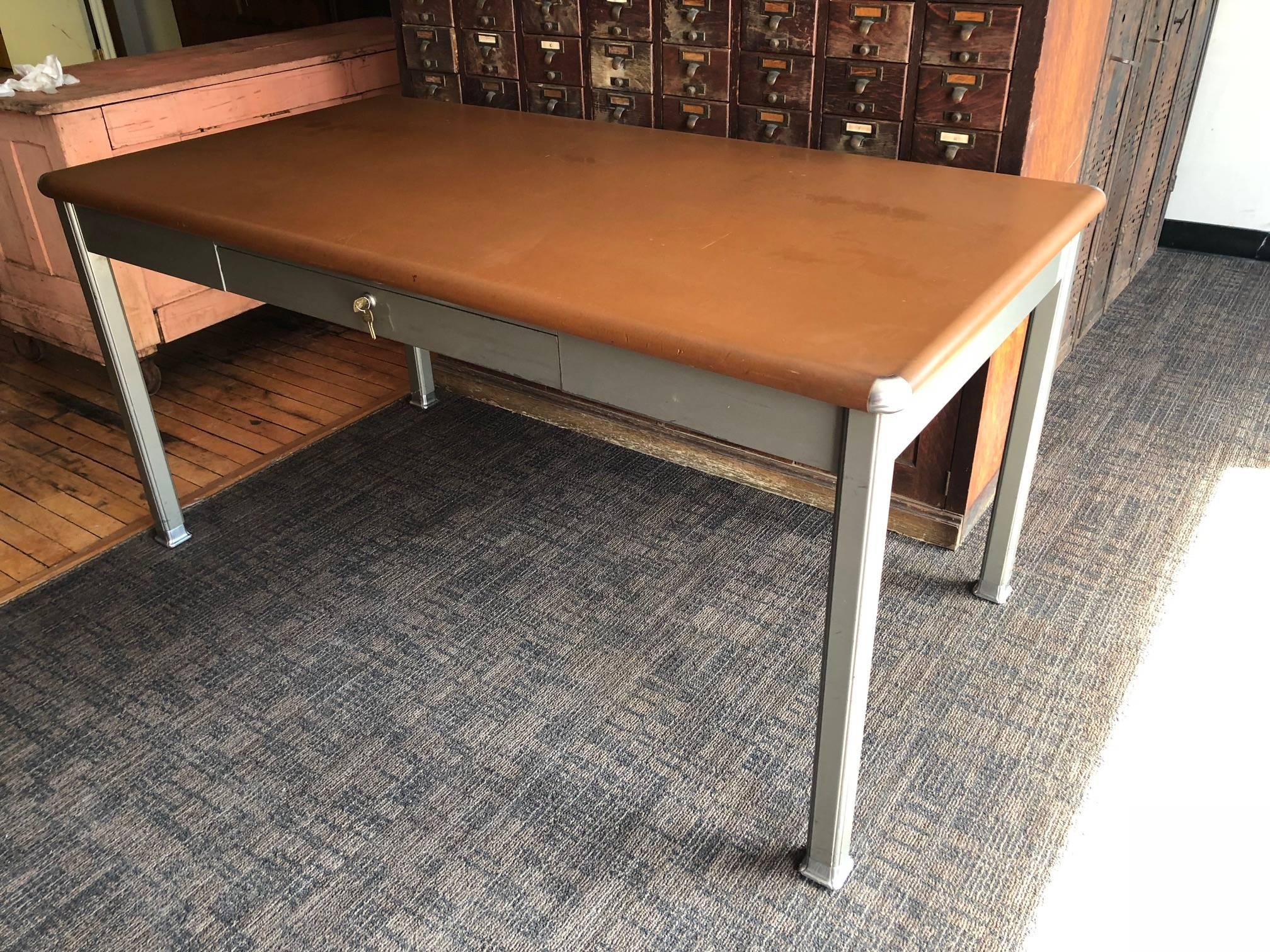 Midcentury Tanker desk with Linoleum top and steel corner bumpers. Minor reassembly of legs to desk top required to keep shipping costs down and assure safe delivery.