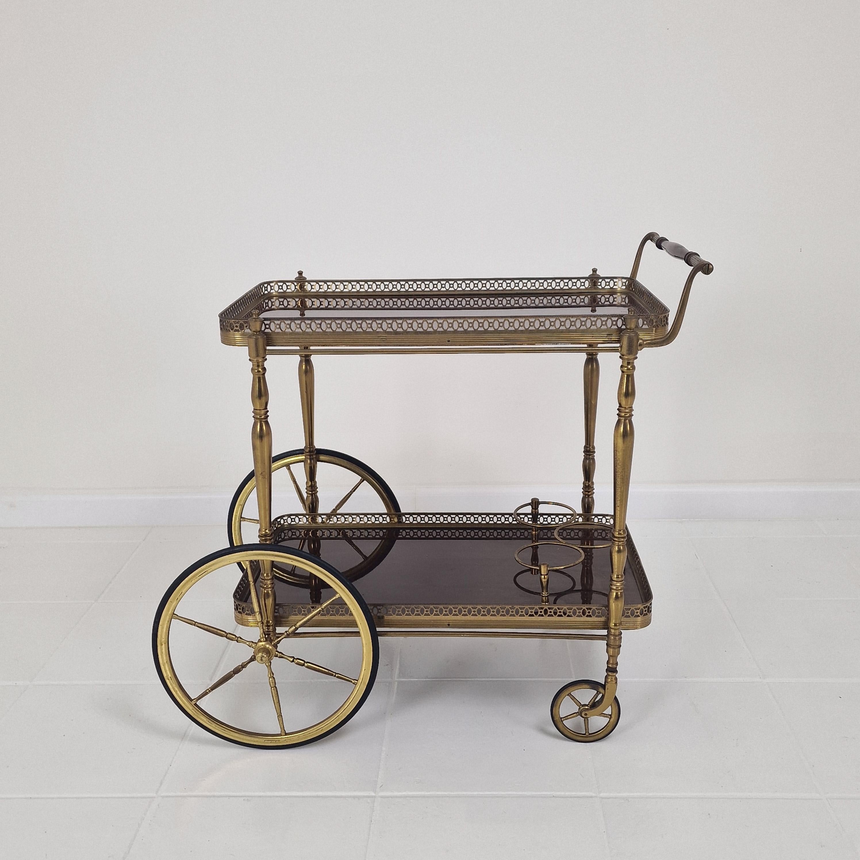 Un élégant chariot de bar des années 1950, ou chariot de service de boissons.
Dans le style emblématique de la célèbre maison parisienne de décoration d'intérieur Maison Jansen. 

Avec son duo de gradins en bois poli et ses galeries en laiton