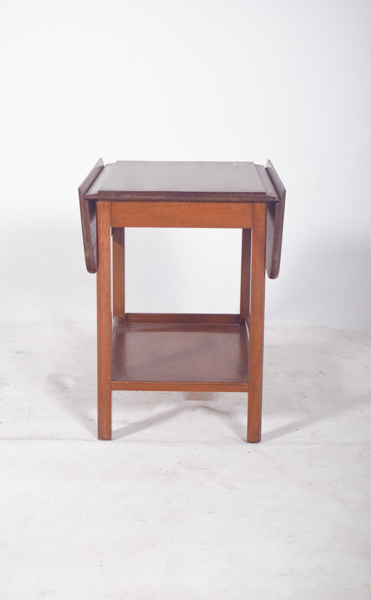 Tea trolley with flaps. The rectangular top has two folding side flaps, which can be lifted to extend the support surface. The structure is made up of four straight legs and a fixed lower shelf, ideal for accommodating trays, bottles or serving