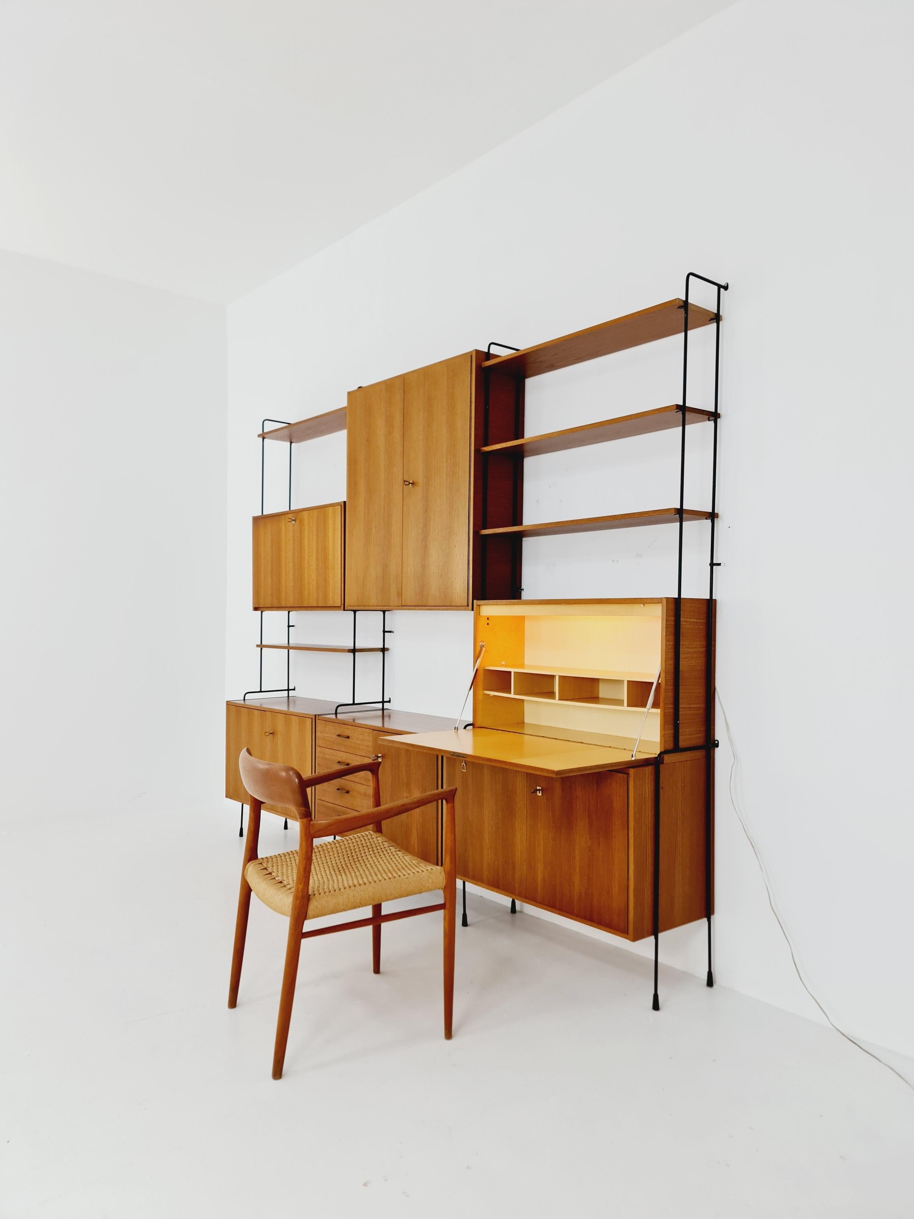 Mid century Teak 8 pieces shelving unit by Hilker for Omnia, Germany 1960s

Designed by Hilker -- The individual units and shelves can have multiple configuration options - Featuring a drinks cabinet & 
 secrtary  The frame is fixed to the wall with