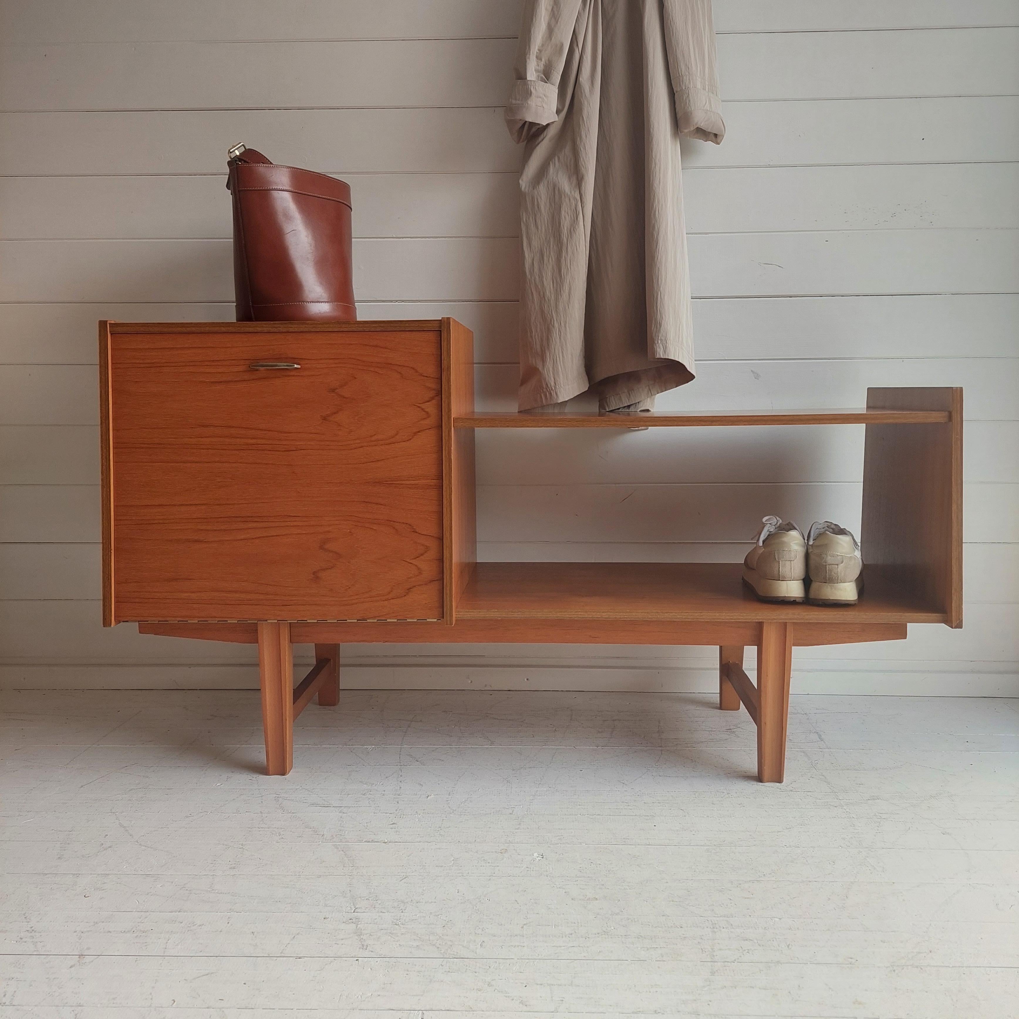This superb sideboard / cabinet/ Hall unit has a real ‘minimalist’ feel to it.
A brithis piece of the 60s

Consisting of a pull down cupboard with brass handle ( with single shelf inside) and a lower shelving/seating area with under shelf
The