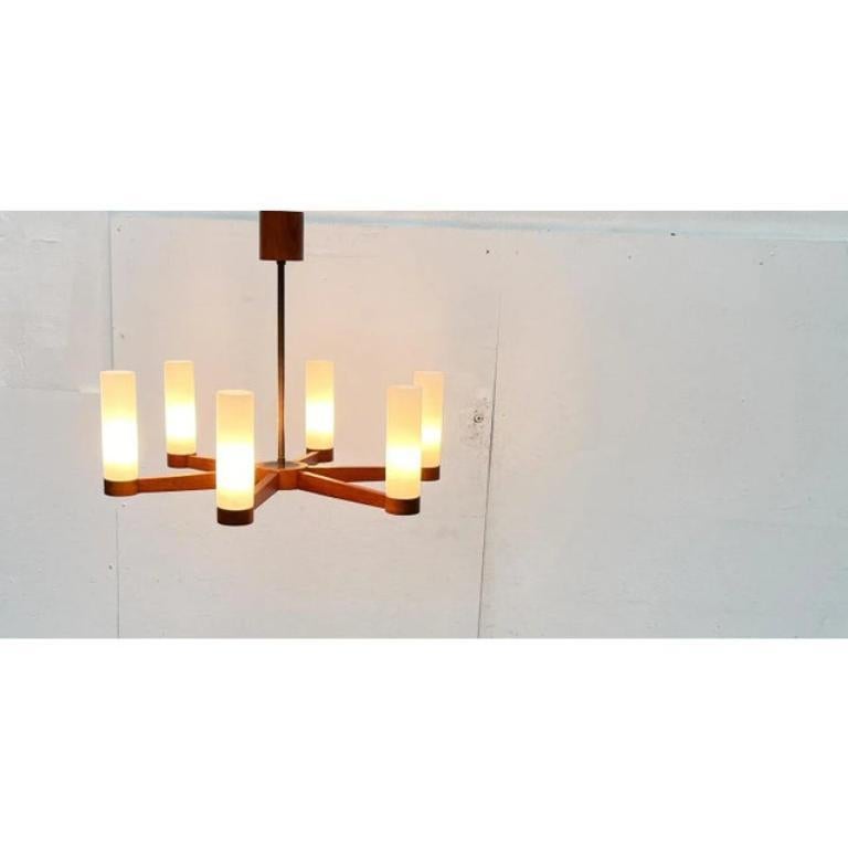 Lampadario da soffitto in teak del metà secolo.

Un design che colpisce per la sua linearità. Sei bracci si estendono a forma di stella da un nucleo centrale. Alle loro estremità si espandono in basi rotonde in cui si trovano le prese. I semplici