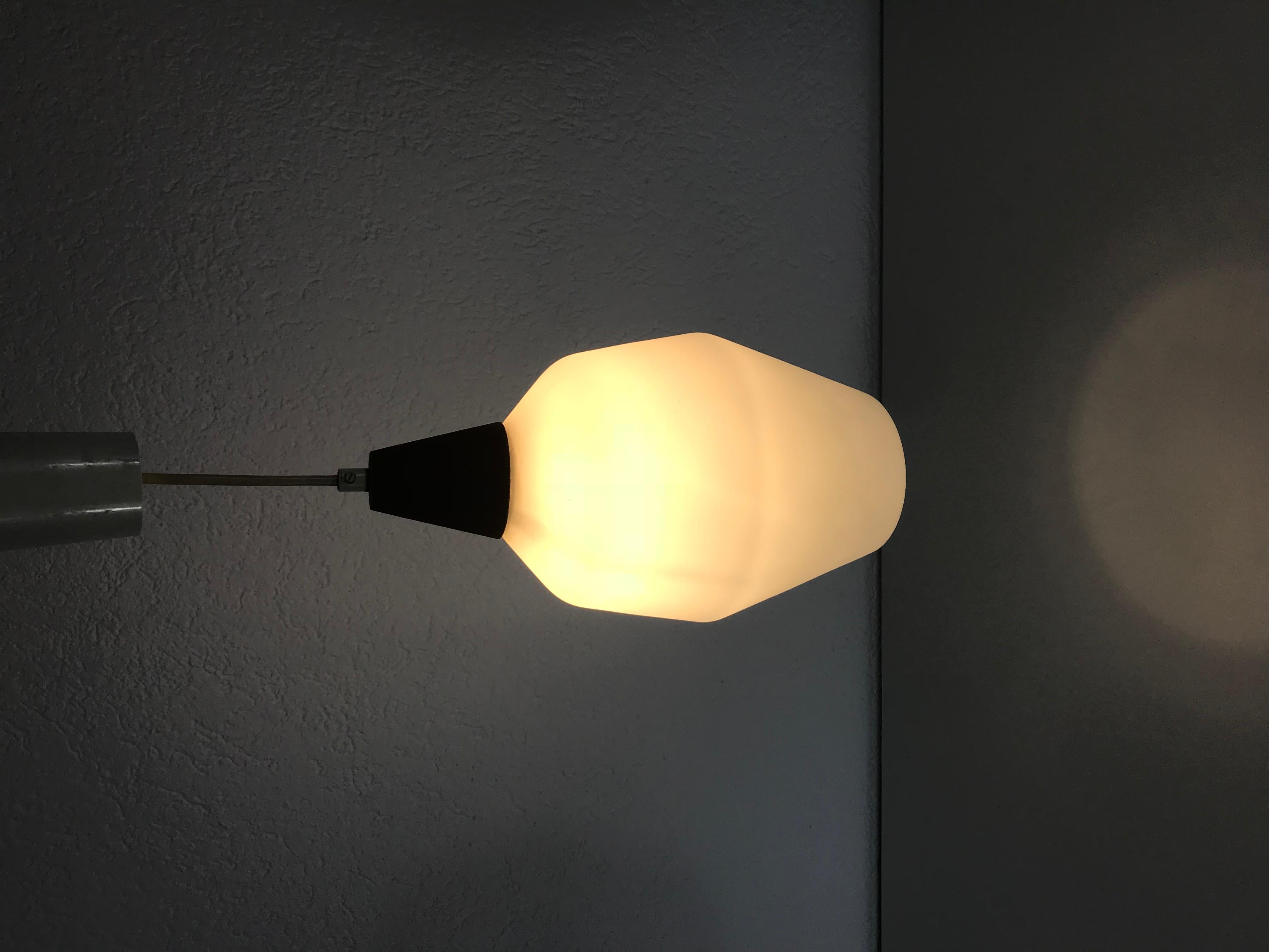 A teak and white opaline glass made in the 1960s. The glass shade is made of thin opaline glassand has an octagonal shape. The top of the lamp is teak. The lamp has a Scandinavian design.

The light requires an E27 light bulb.