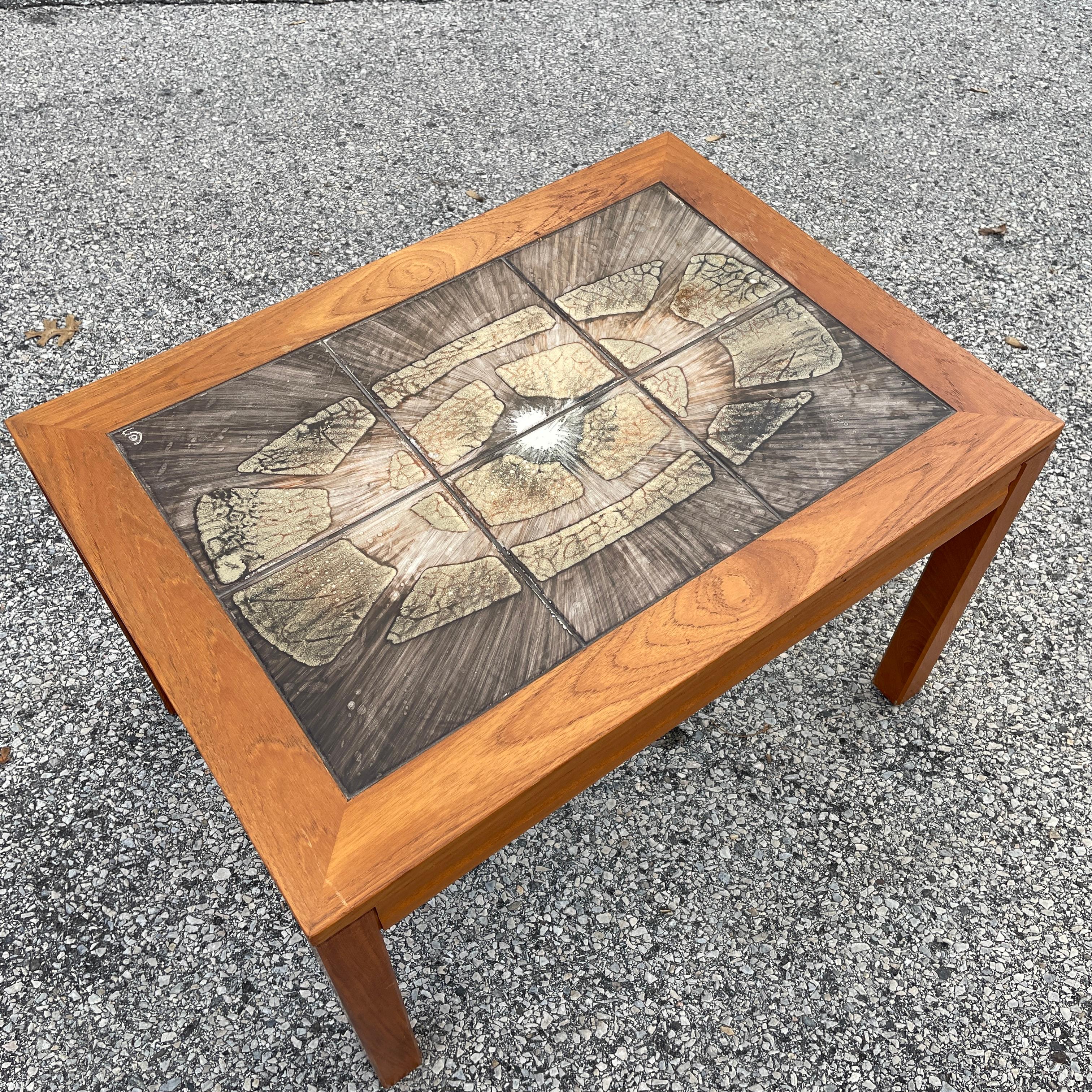 A mid-century side table with a teak frame and tile top. Signed with an 