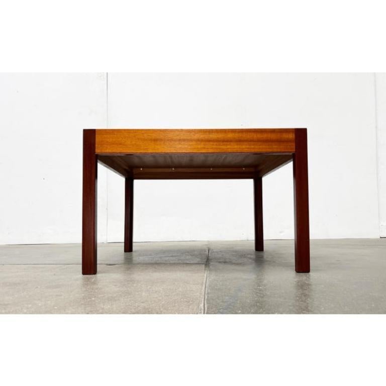 Table basse carrée du milieu du siècle en teck et noyer.

Un design avec une combinaison frappante de matériaux. La table est principalement fabriquée en teck. Les pieds sont en noyer et ont une finition foncée. Une autre particularité est le design