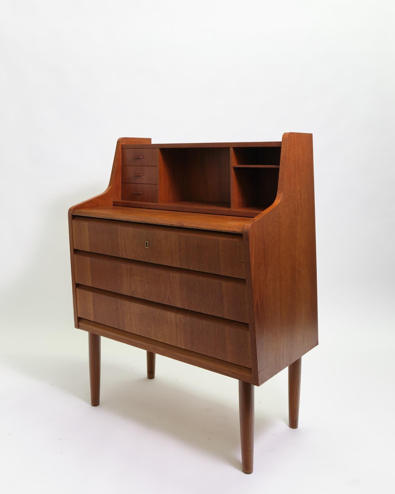 Mid-century teak bureau table circa 1960s/70s, with three small drawers and galley over three long drawers.

Dimensions: H100 x W80 x D45 cm.