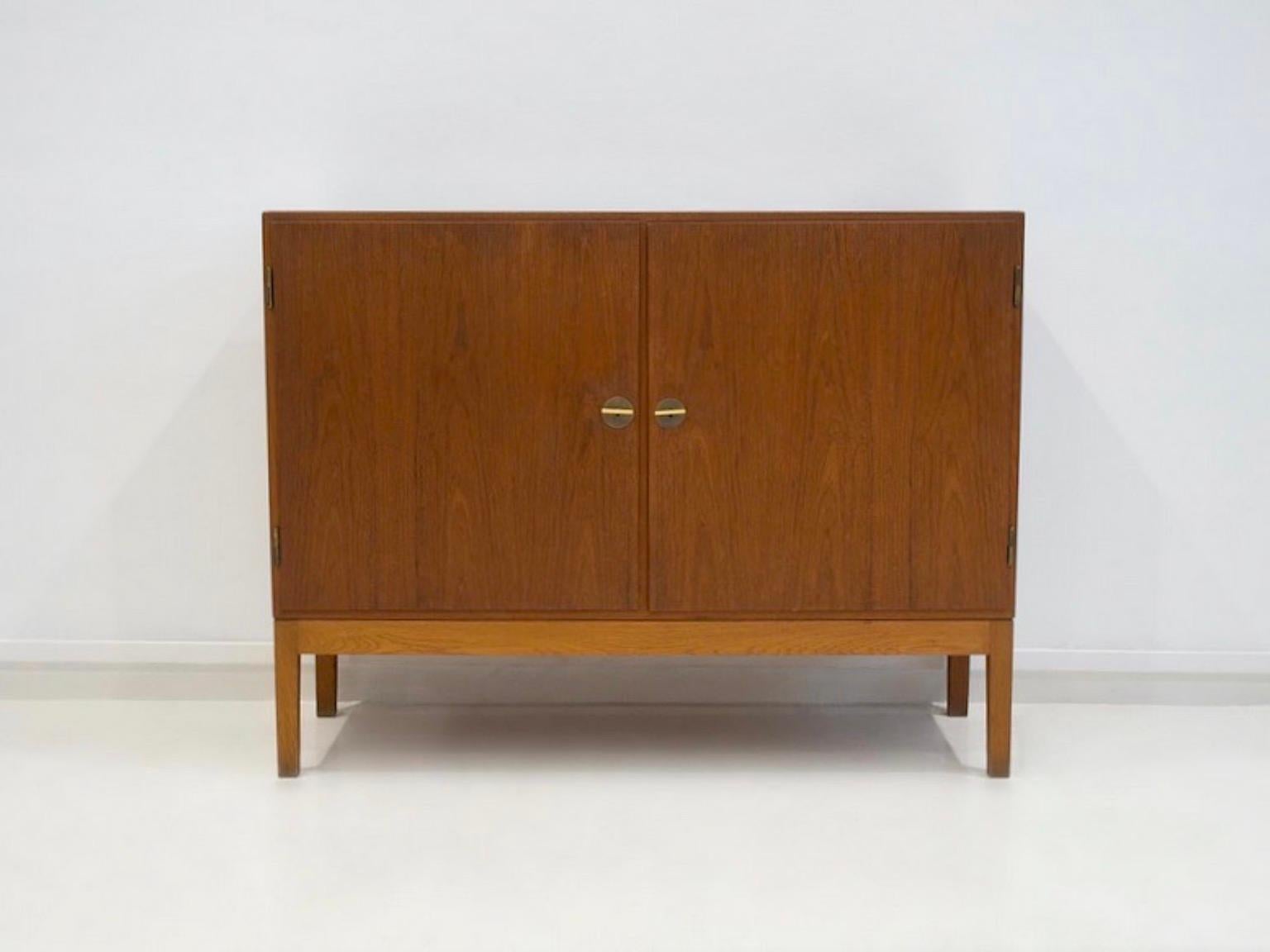Credenza Børge Mogensen in teak con due ante nella parte anteriore. Interno con ripiani e vassoi estraibili. Tieni presente che i piedi non sono originali e sono realizzati in Oak. In seguito sono state aggiunte anche delle chiavi in ottone che
