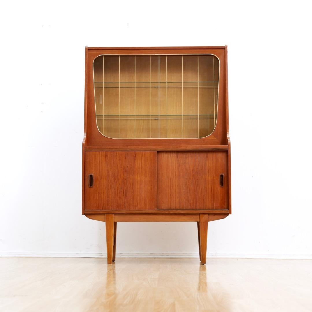 This mid-century China display cabinet was produced in England during the 1960s. Made from rich teak the top section has a china storage cabinet with sliding glass doors, the bottom has shelved storage behind sliding wooden doors. 