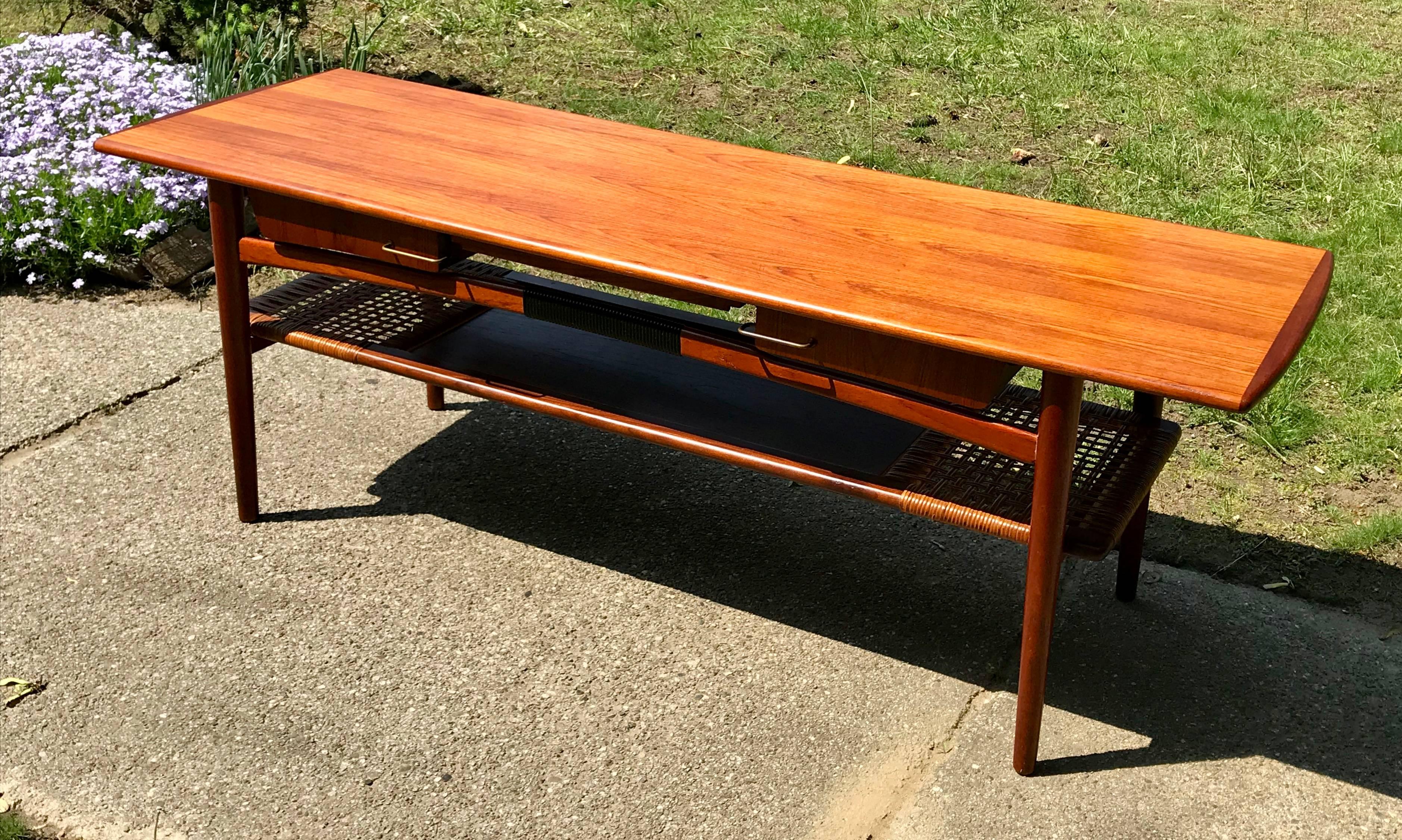 Very stylish teak coffee table with pull-out laminate cocktail shelf along with four side drawers and woven cane bottom shelf, Denmark, 1960s. All original, professionally cleaned, small loss of cane though very minor, please see photos.
