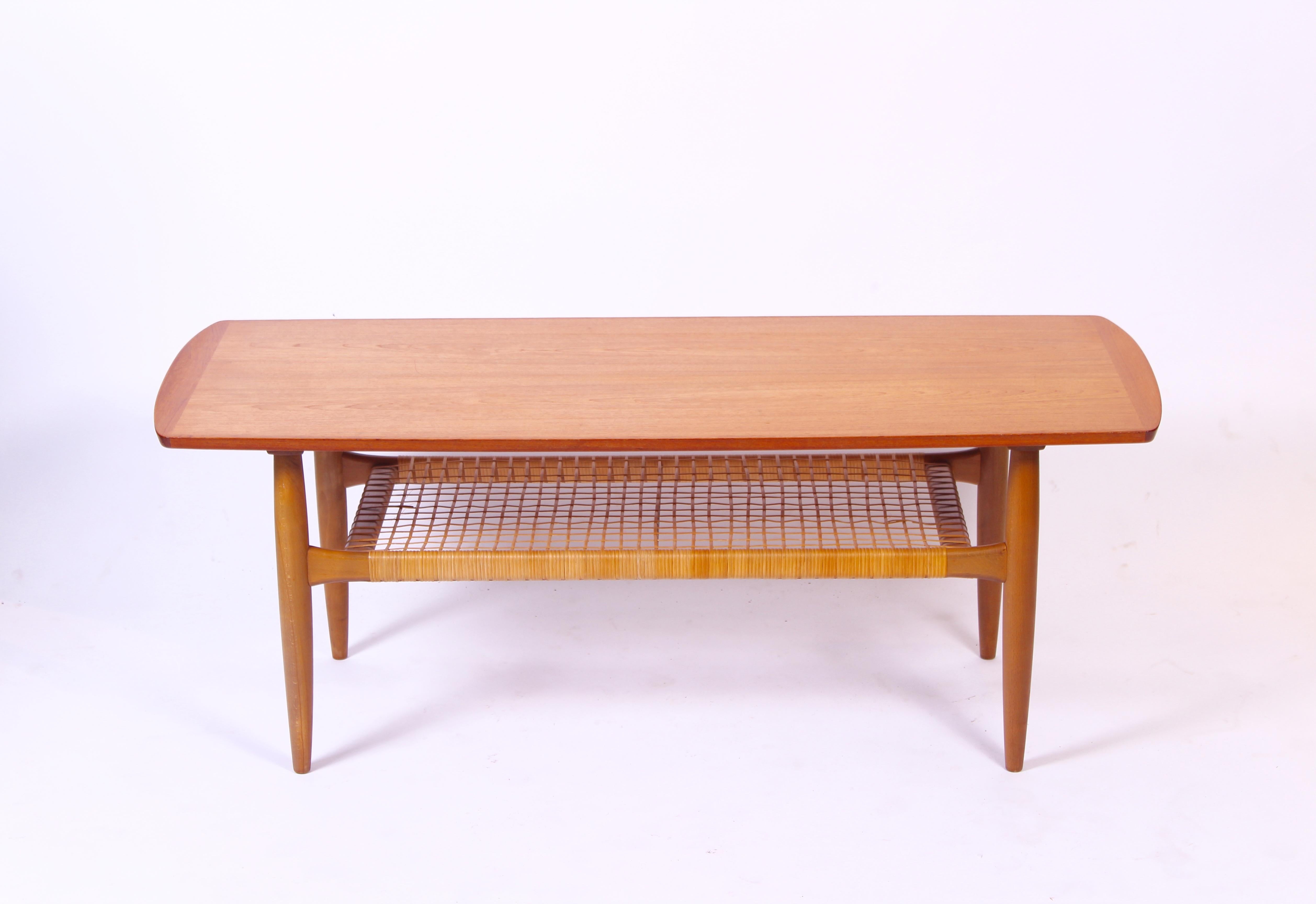 A beautifully designed coffee table from the mid-20th century by Danish designer Kurt Østervig. The table was produced by Danish furniture manufacturer Jason Møbler in the 1950s. Excellent details such as the rattan shelf, tapered legs and elevated