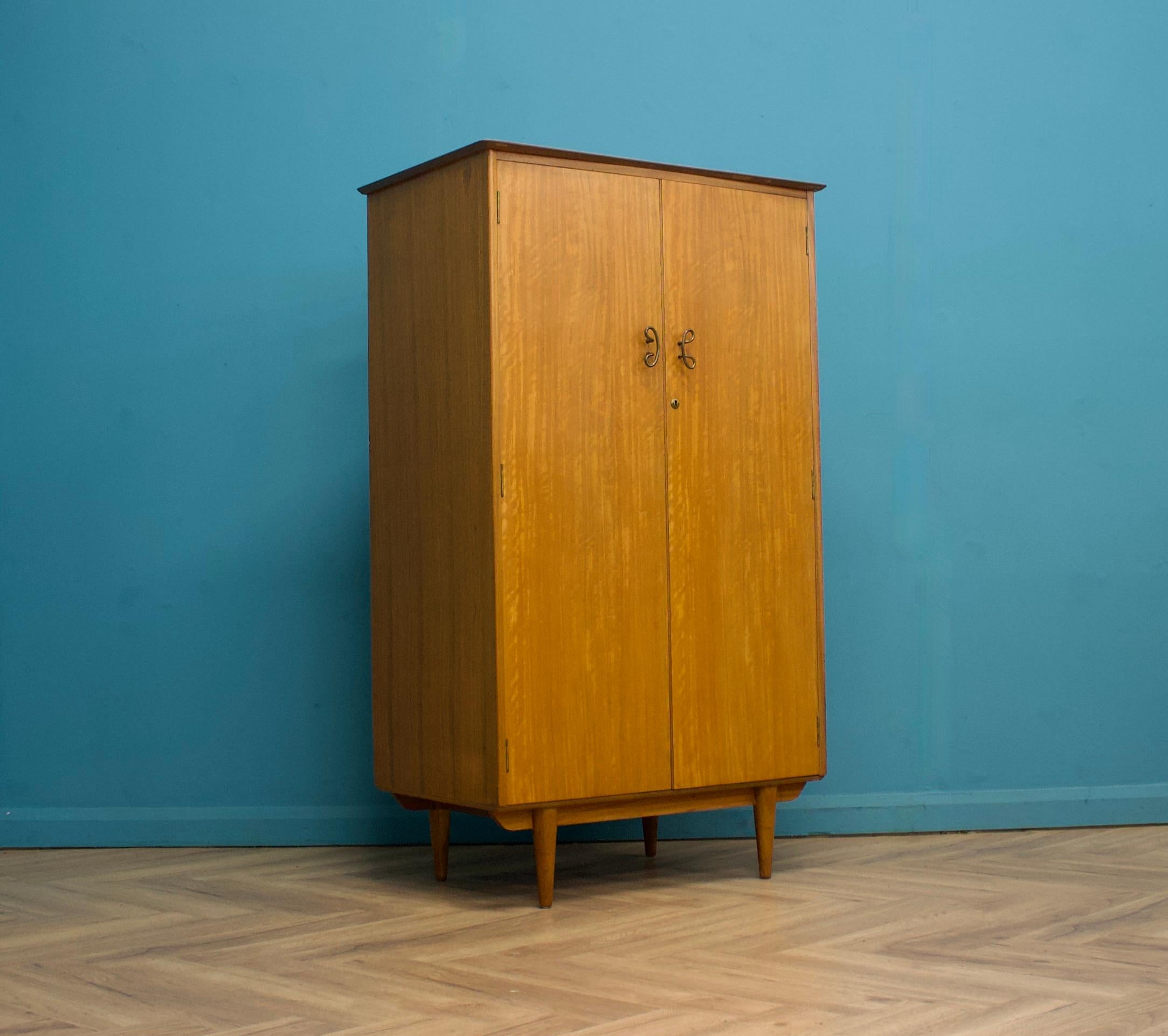 Armoire compacte en teck du milieu du siècle de Younger, vers les années 1960.

L'armoire comprend une tringle à vêtements, trois étagères fixes et deux tiroirs.
