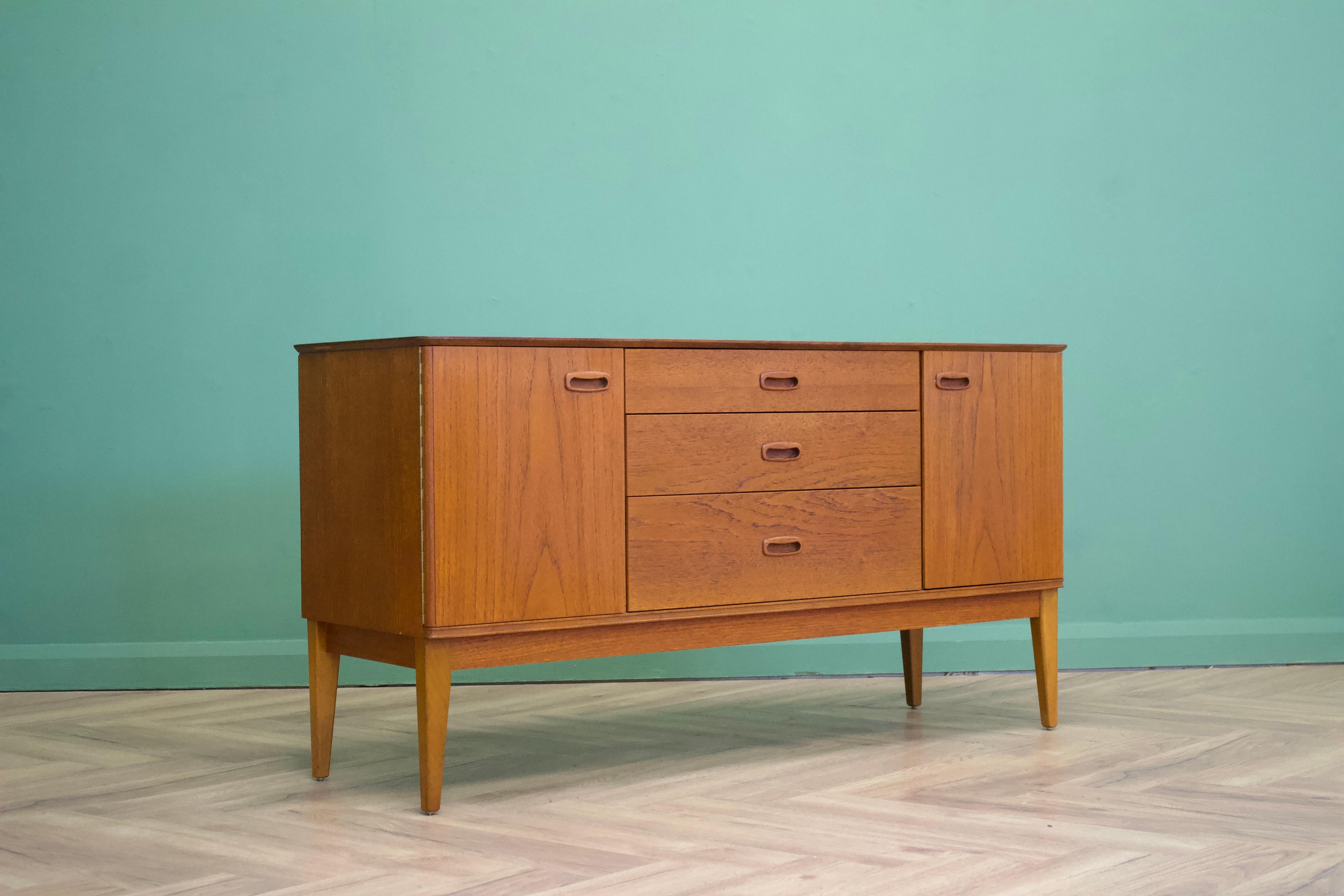Mid-Century Modern sideboard from Austinsuite
Manufactured in the UK
Made from solid teak and real teak veneers
Featuring two cupboards and two drawers.