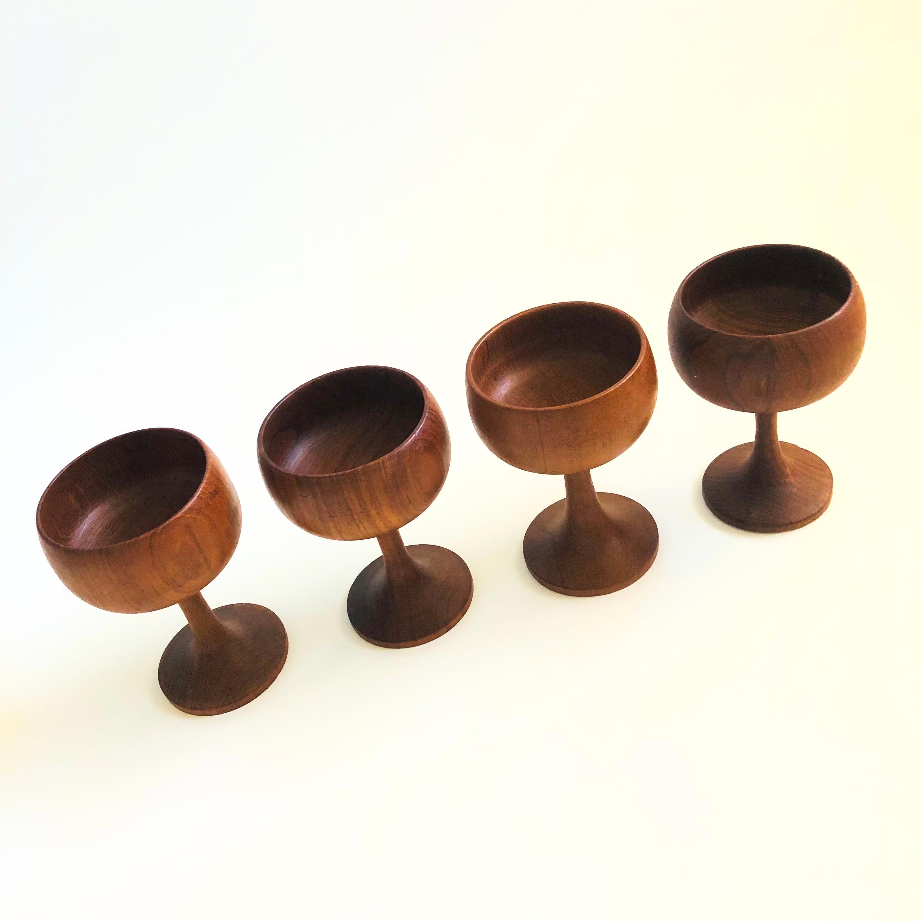 A set of 4 mid century turned teak coupes. Elegant shapes with tapered stems and a beautiful grain to the wood.

